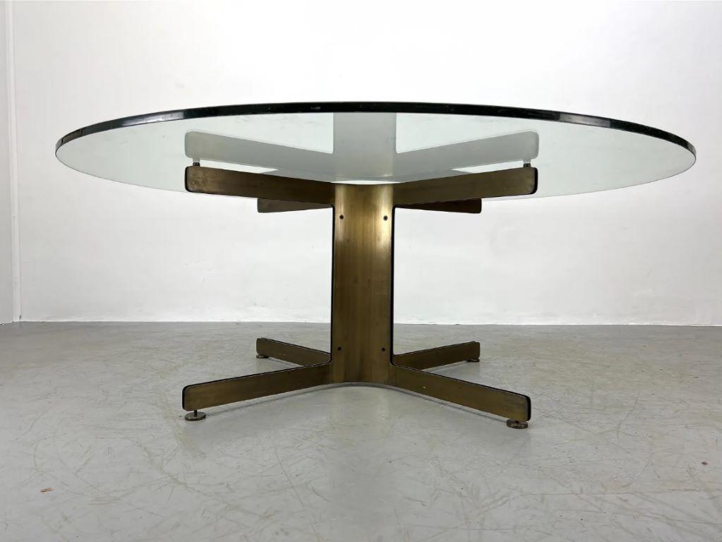 Midcentury Italian bronze pedestal dining table with round glass top, in the style of Osvaldo Borsani. Wide extended supports and adjustable feet on the pedestal base lend additional stability.