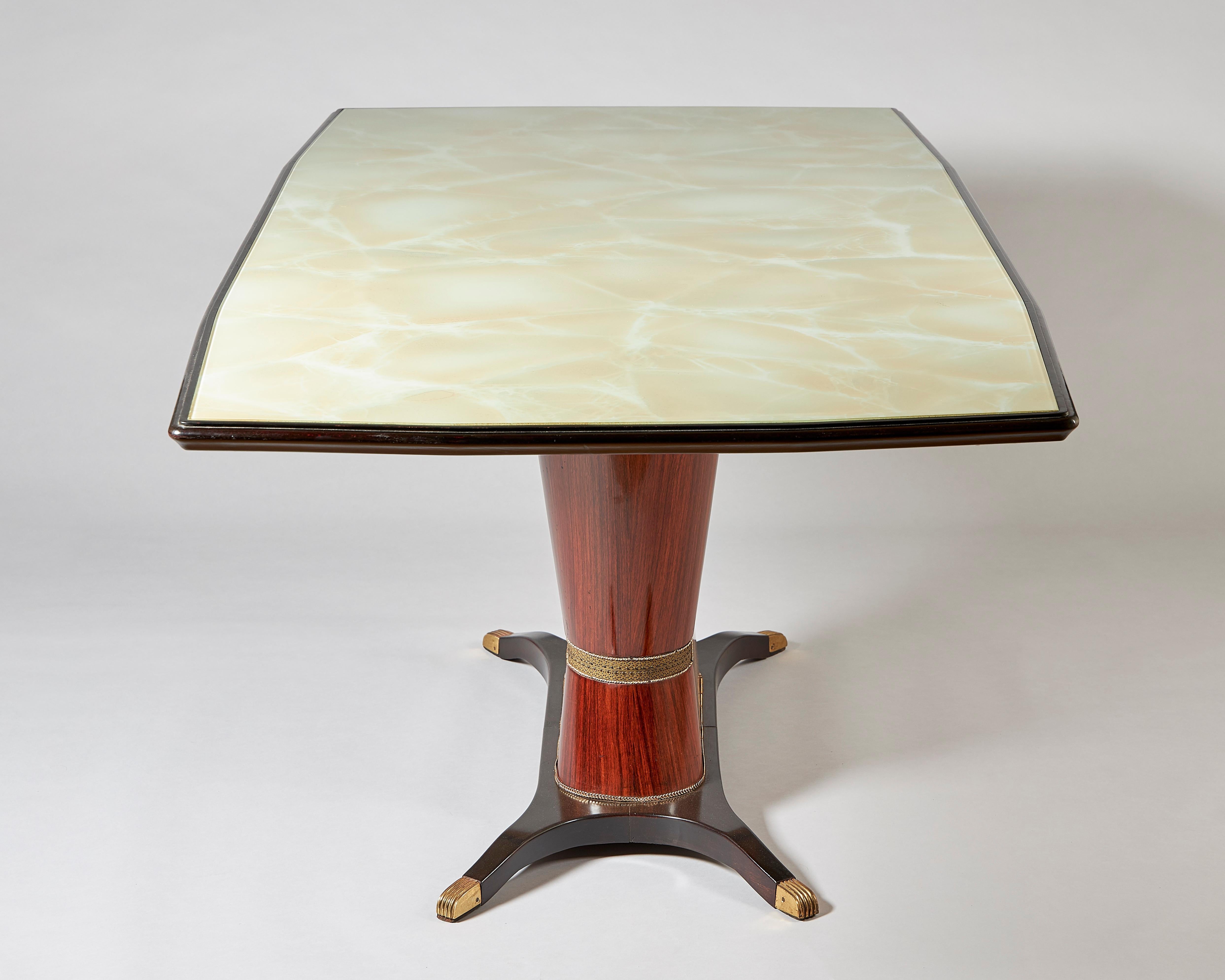 An Italian rosewood dining table, designed by Osvaldo Borsani, circa 1950.
With simulated onyx and glass top, the base with pierced brass inlay.