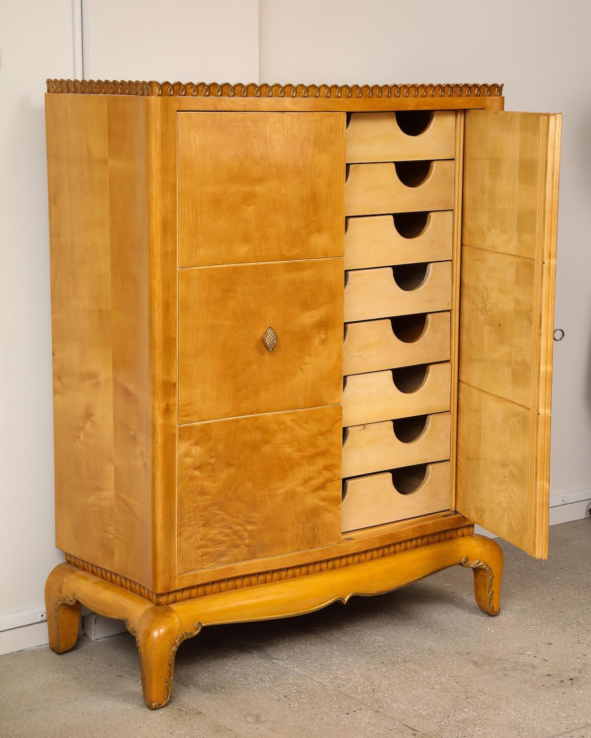 Wardrobe Unit by Osvaldo Borsani for ABV. Maple, burled maple, painted wood. Cabinet with stylized feet, carvings and gold-painted accents. Doors open to reveal 8 interior drawers. Exterior wood has been recently refinished.
Provenance: Borsani