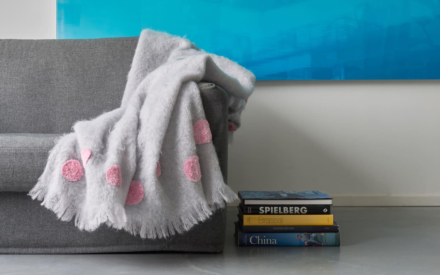 Otago, a beautiful pearl grey throw blanket made of the finest New Zealand mohair. Characterised with pink big dots, completely embroidered by hand. A tone-on-tone fringe runs along the border. A throw like this, can transform instantly a space. 
We