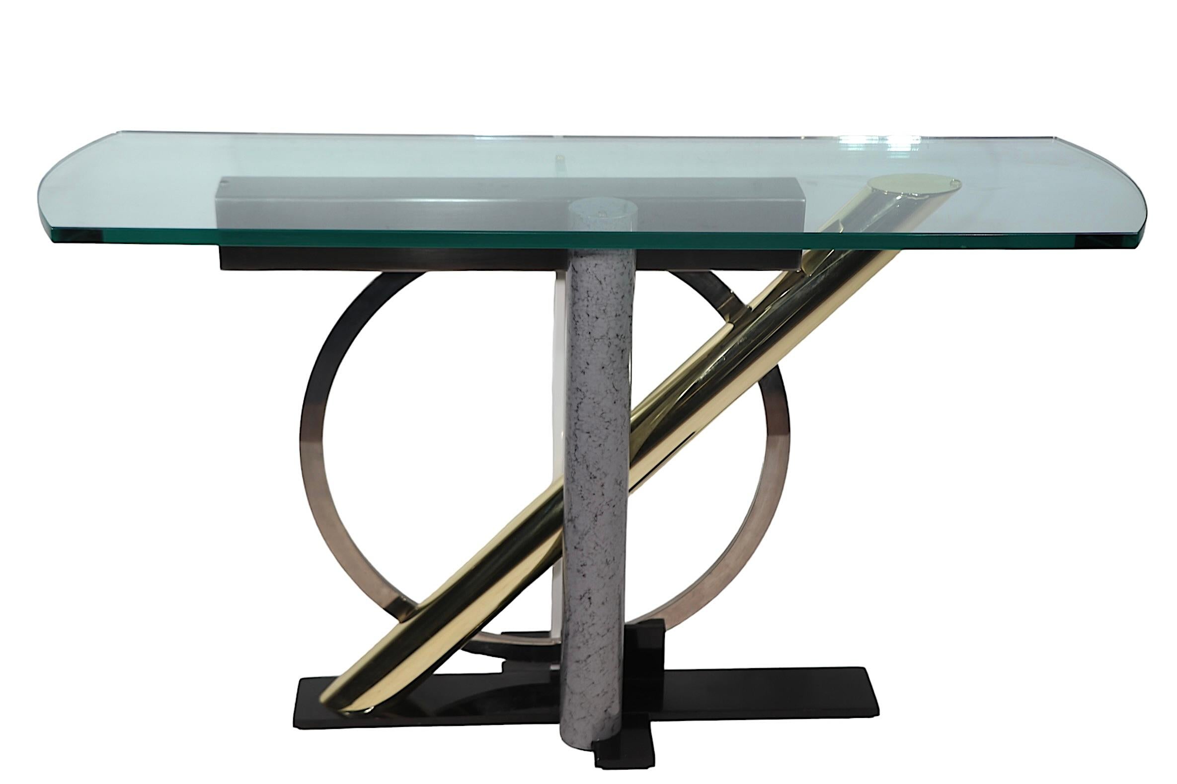 Iconic Post Modern design console table by Kaizo Oto for the Design Institute America, circa 1980's. The table features a thick shaped glass top which rests on the stylized mixed metal base. This example is in excellent, clean, original, and ready