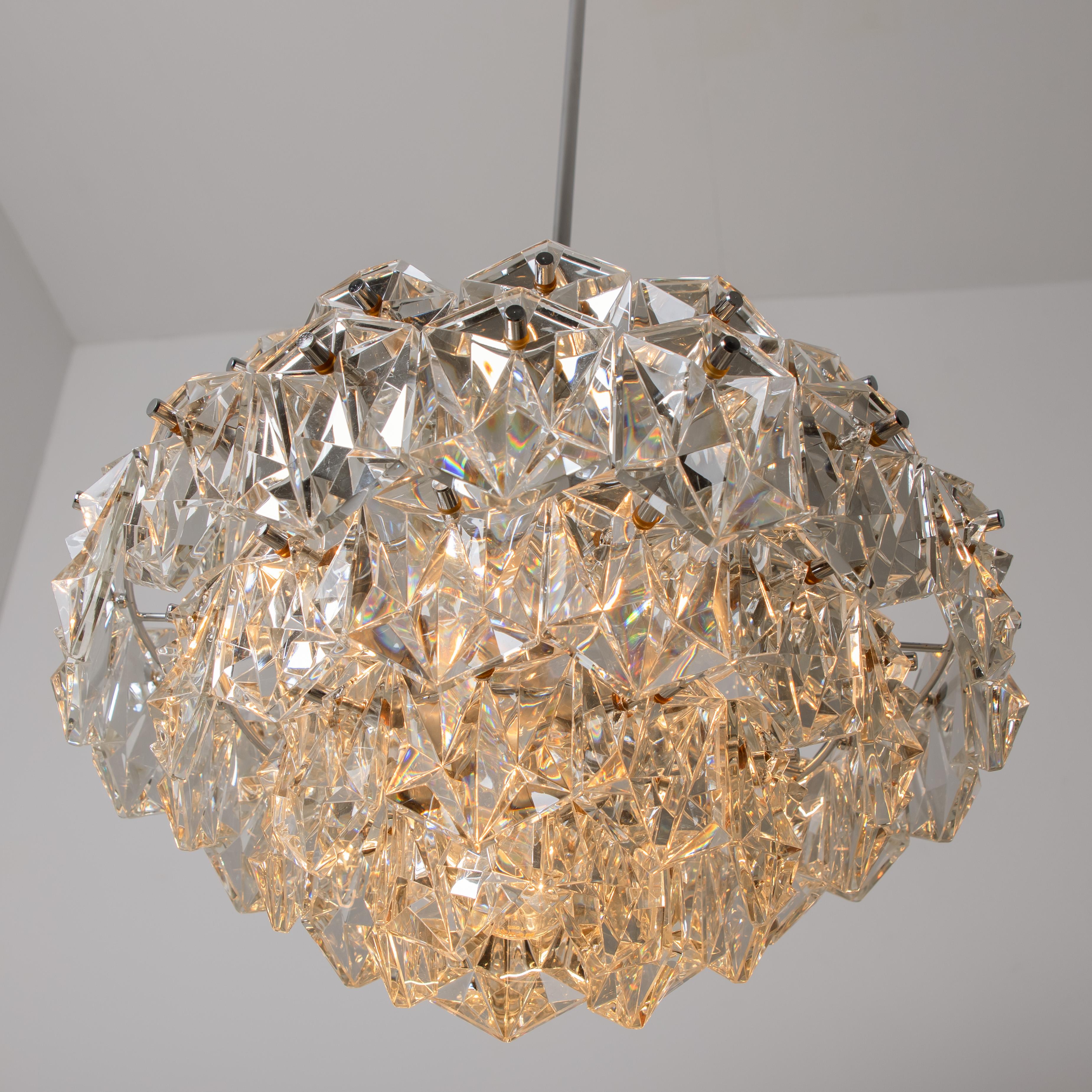 This modernist design chandelier is designed by the OTT International design team during the 1970s, and manufactured in Germany. This chandeliers are executed to a very high standard: All metal parts are chrome plated, even the lamp sockets and