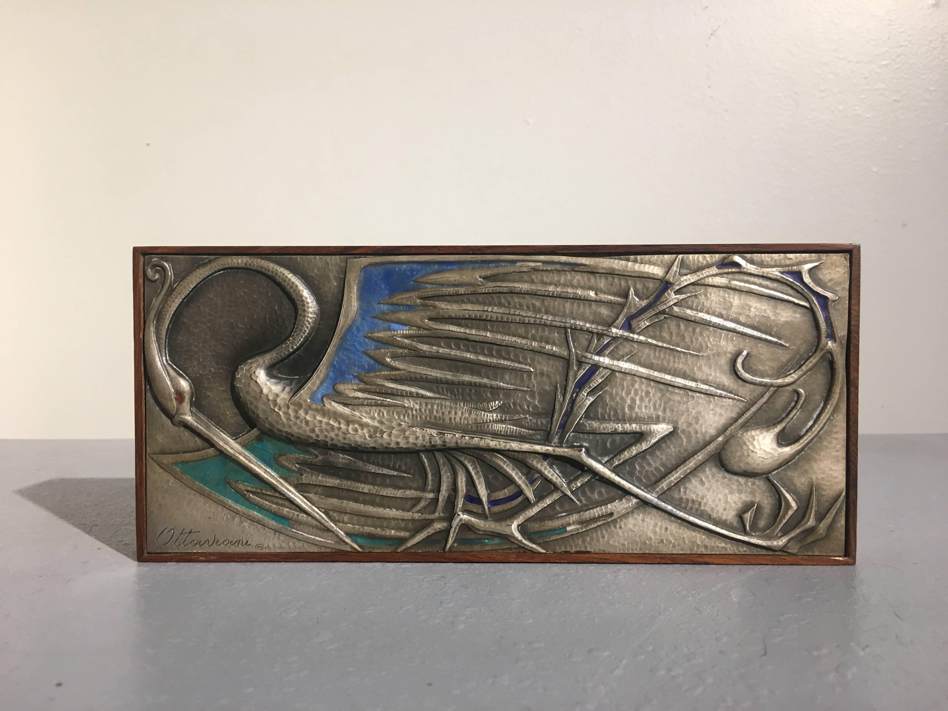 A stunning enameled silver and rosewood box signed Ottaviani, Italy, circa 1950s.
The top of the box features a gorgeous repousseed and hand hammered sterling silver inset plaque with a design of a fantastic bird. The wings have been embellished