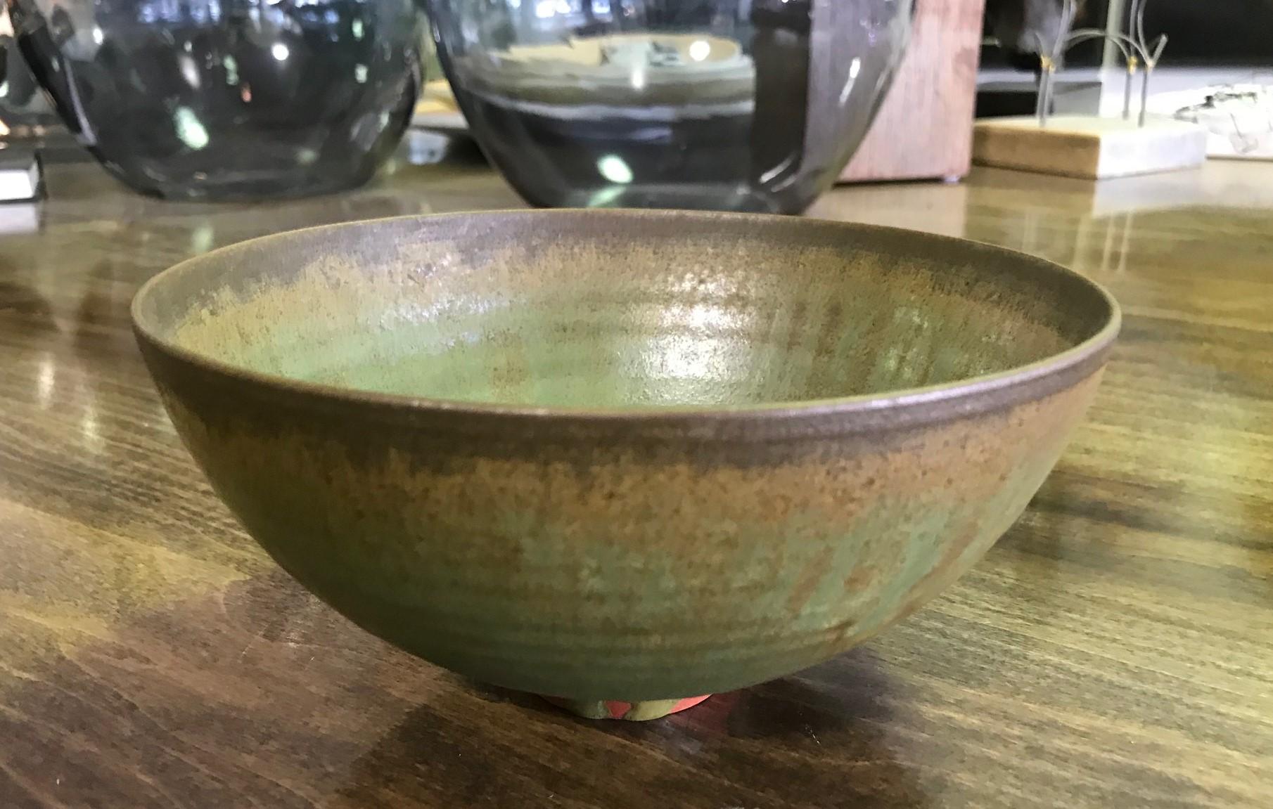 A masterful work by famed potters Otto and Gertrud Natzler. This round-shaped footed bowl was wheel thrown and formed by Gertrud and glazed by Otto with a rare dripped green lava glaze. The bowl captures your attention from all angles. You won't