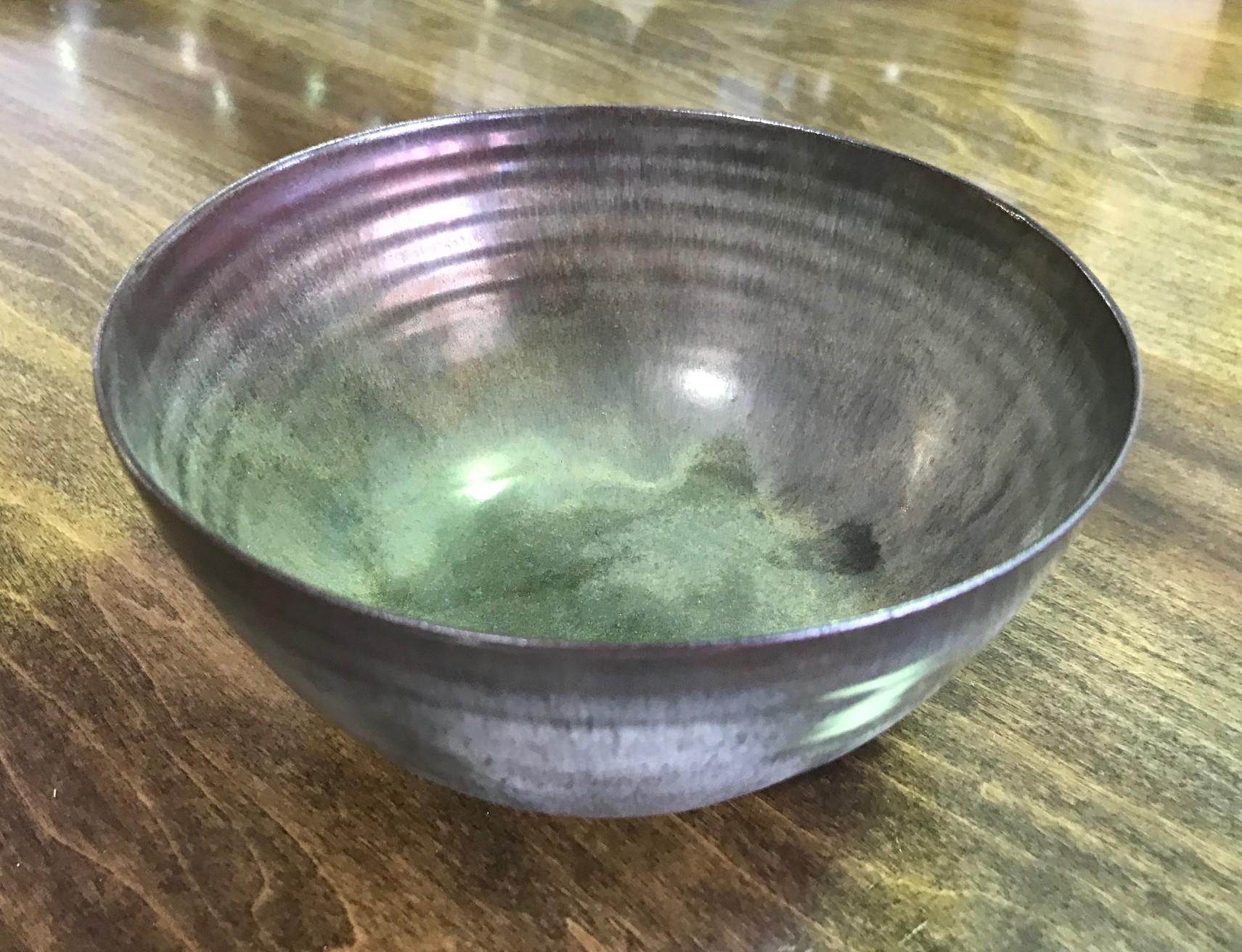 A masterful, rich work by famed potters Otto and Gertrud Natzler. This round-shaped footed bowl was delicately hand thrown and formed by Gertrud and glazed by Otto with a gorgeous dark, blue-grey crystalline reduction glaze. The bowl captures your