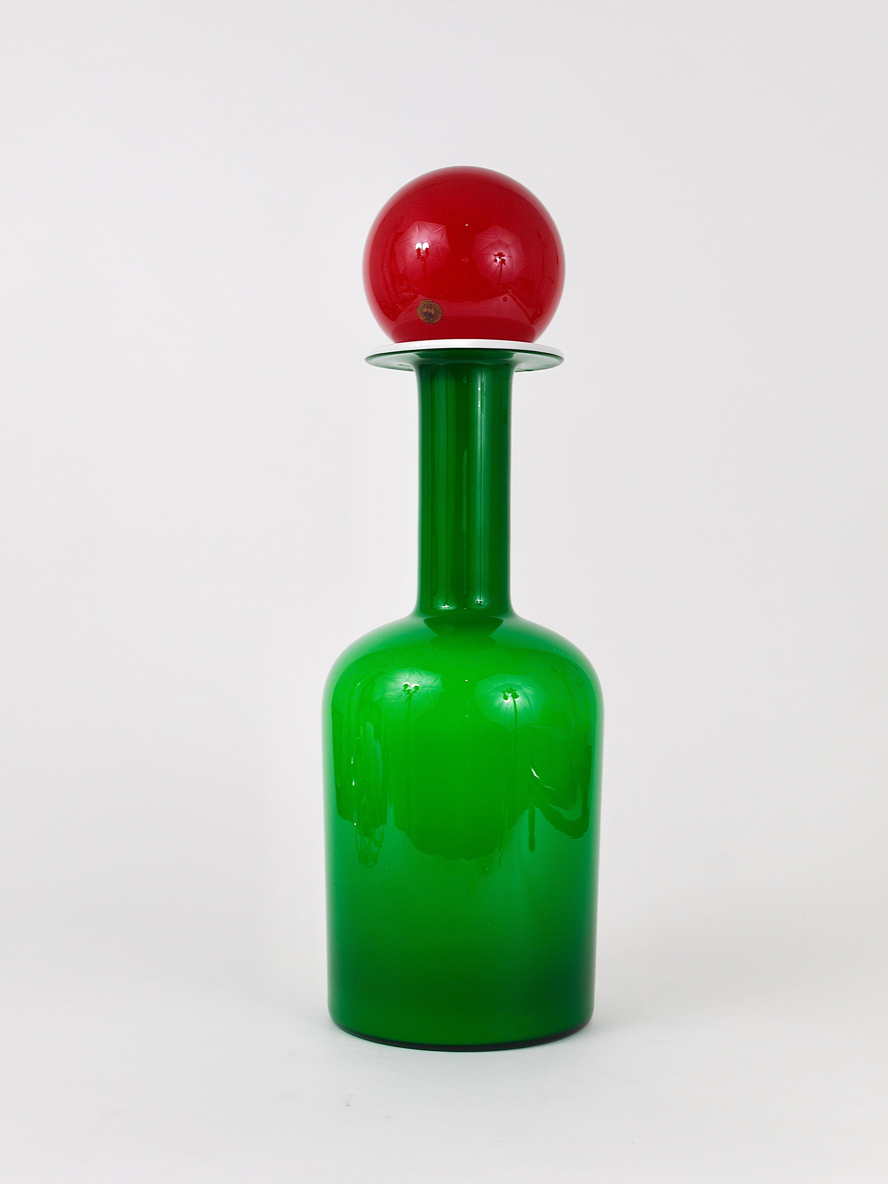 A beautiful 21.5 inches tall Danish modern Midcentury bottle vase with red ball stopper, designed by Otto Bauer in 1959, manufactured by Holmegaard Kastrup / Denmark in the 1960s. Handmade of two layers of green and white glass, gradient from green