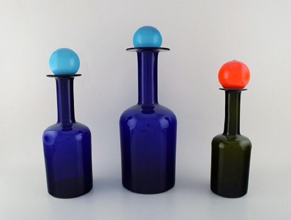 Otto Brauer for Holmegaard. A collection of five large vases / bottles in dark blue and green art glass with lids in the shape of a ball, 1960s.
Largest measures: 42 x 15 cm.
In perfect condition.