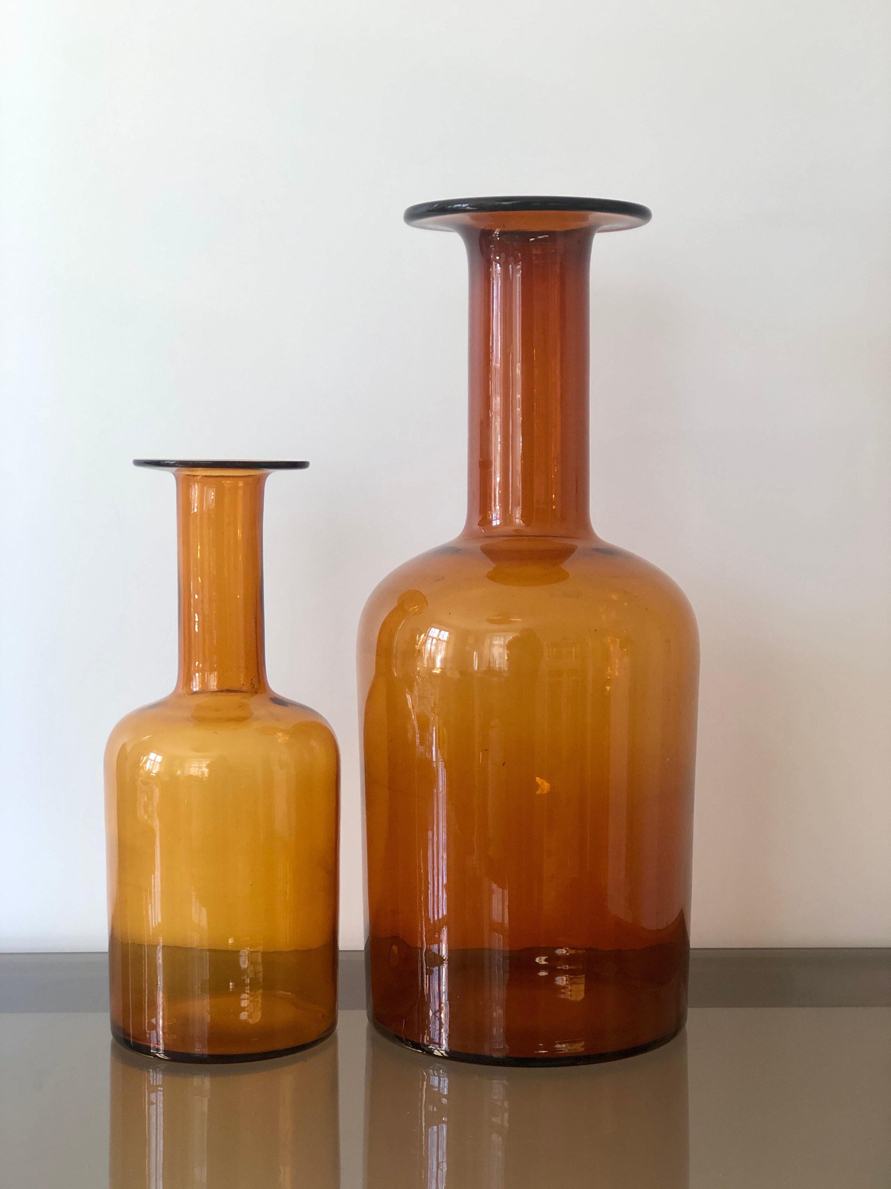 A pair of Mid-Century Modern iconic Gulv vases by Otto Brauer in amber color. Manufactured by Holmegaard Denmark in the 1960s. Original sticker at the base on the taller vase, bubble inside the glass from manufacturing at the base of the taller vase