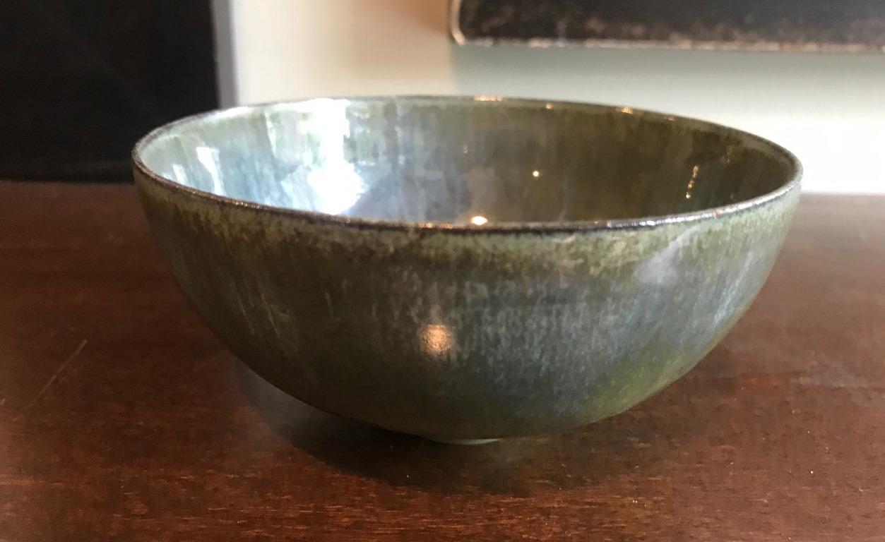 Another wonderfully glazed and delicately designed work by famed pottery masters Otto and Gertrud Natzler. This round-shaped, eggshell thin-walled bowl was hand thrown and formed by Gertrud and glazed by Otto with a beautiful dark blue or green