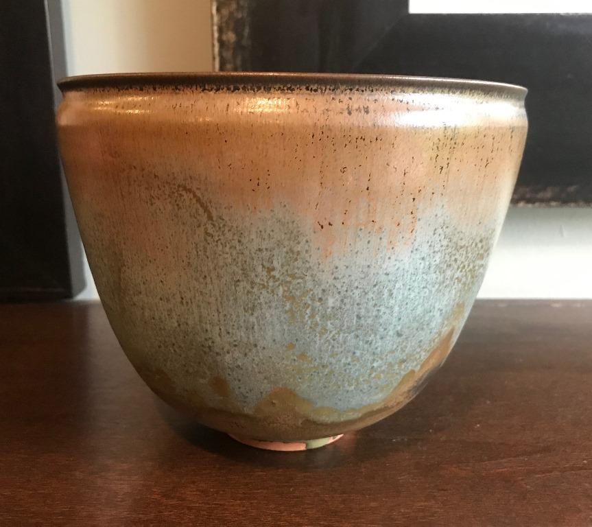 A wonderful work by famed pottery masters Otto and Gertrud Natzler. This large, round-shaped footed bowl was hand thrown and formed by Gertrud and glazed by Otto in shades of green and brown with light blue highlights on both the inside and outside.