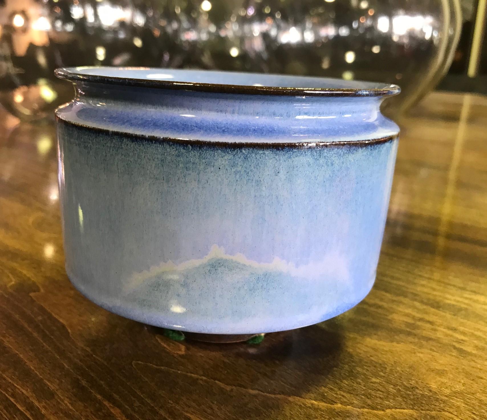 Another wonderfully glazed and rare shaped work by famed pottery masters Otto and Gertrud Natzler. This round light blue glazed bowl has a beveled rim and design which tapers towards the bottom into a narrow round foot. The bowl glows in the light.