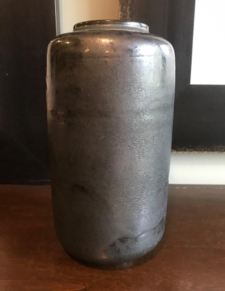 A tall, darkly glazed work by famed pottery masters Otto and Gertrud Natzler. This large vase was hand thrown and formed by Gertrud and glazed by Otto with a darkly hued metallic black crystalline glaze. The bowl glows in the light. Rare in shape