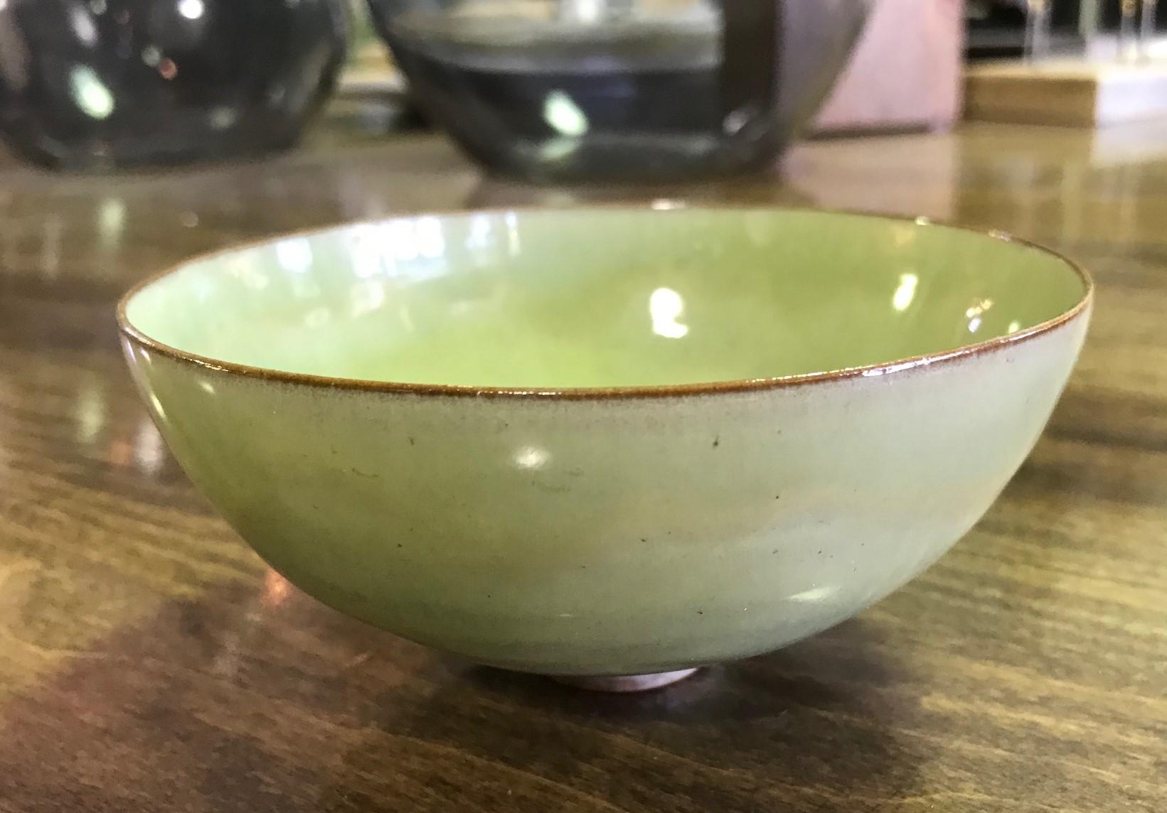 A wonderfully glazed and delicately designed work by famed pottery masters Otto and Gertrud Natzler. This round-shaped, eggshell thin-walled bowl was hand thrown and formed by Gertrud and glazed by Otto with a beautiful lime green glaze. The bowl