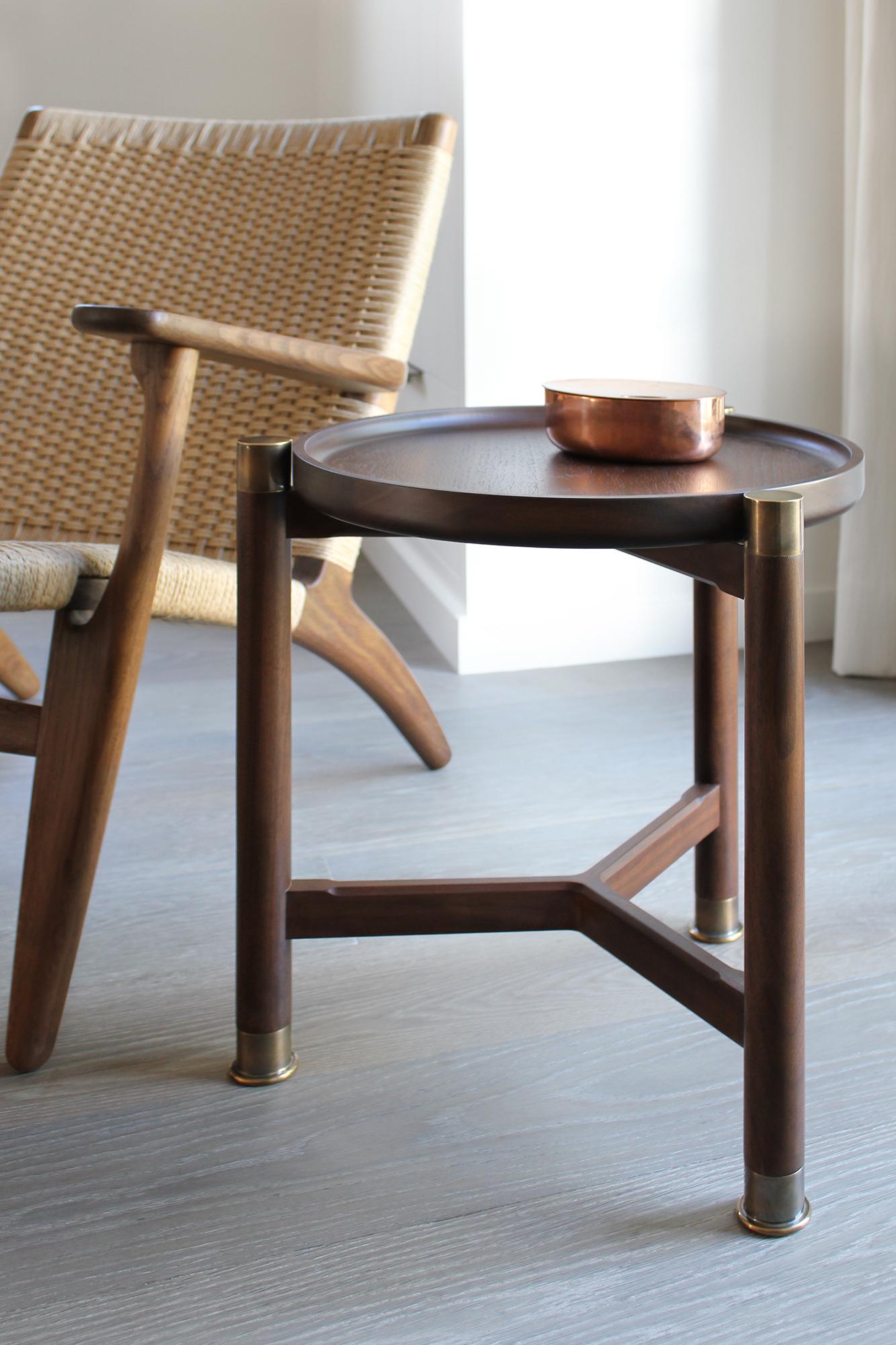 The Otto accent table is a small-scaled table with a Classic, simple, form. 
Available in walnut or oak, it features a round coupe top, substantial antique brass fittings and sleek chamfered stretchers. The epitome of understated elegance - it