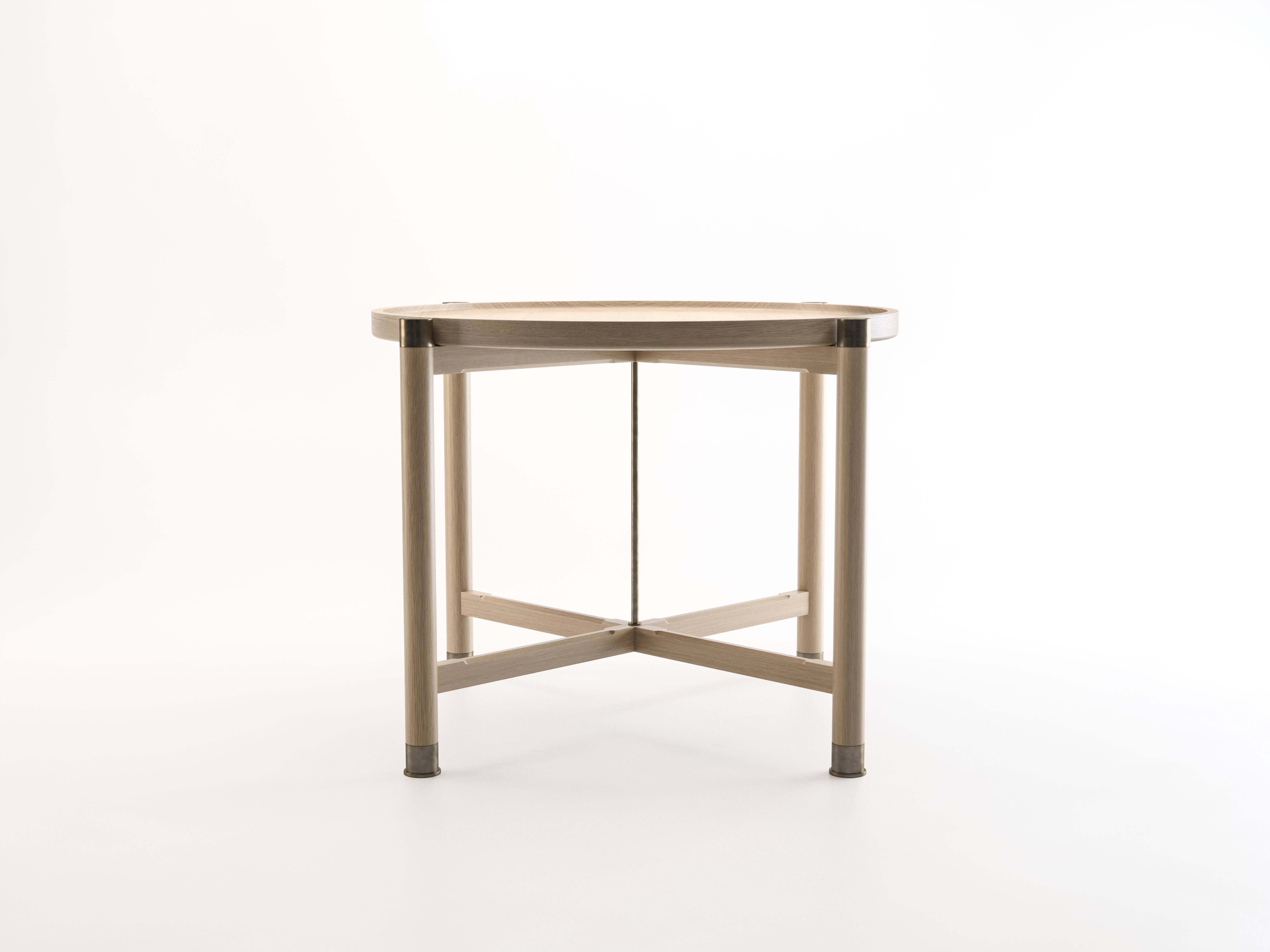 The Otto side table is a generously proportioned table with a simple, well-articulated form.
Available in oak or walnut, it features a round coupe top, substantial antique brass fittings, a central brass stem, and sleek chamfered stretchers. The