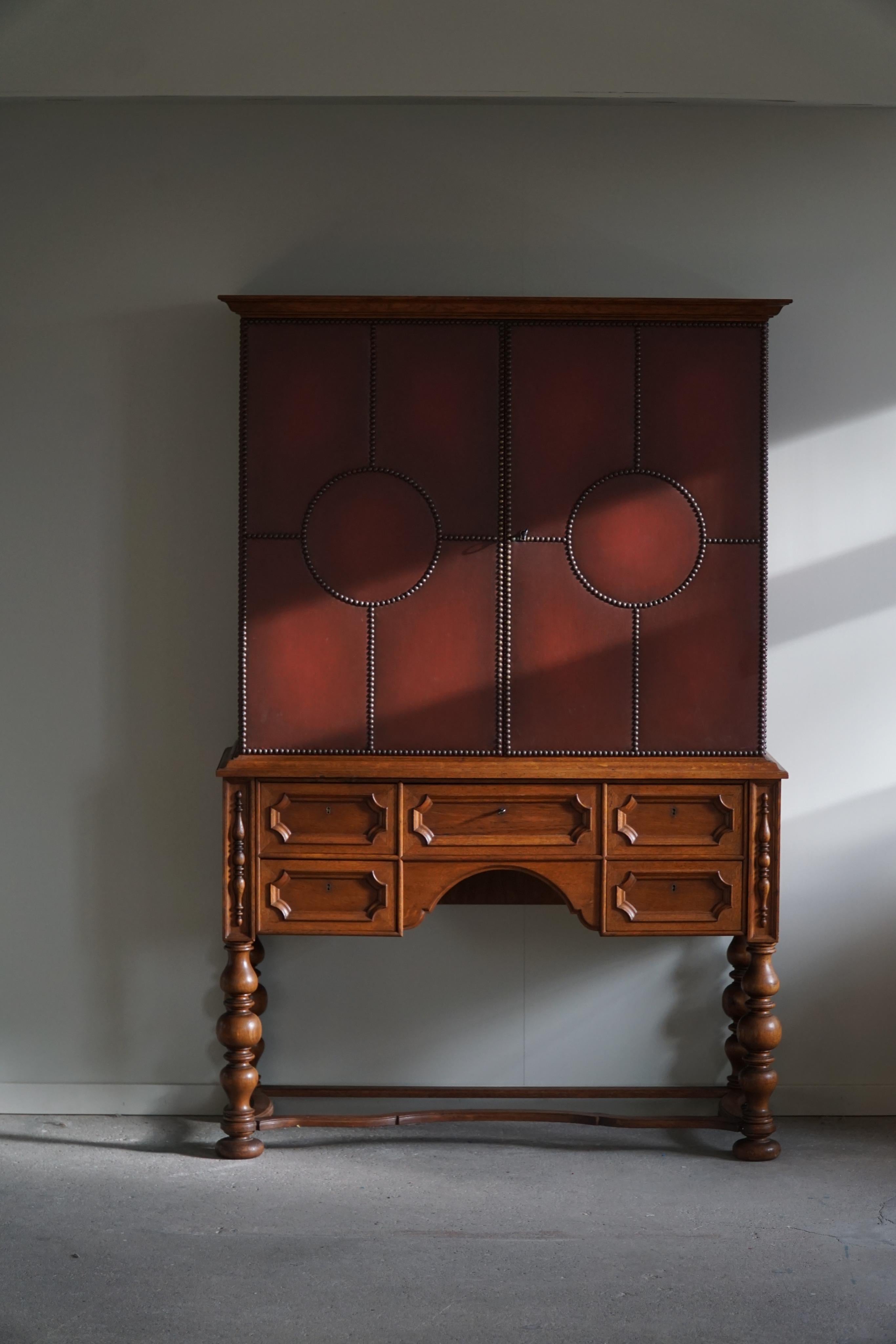 Une armoire exclusive attribuée au célèbre designer de meubles d'origine allemande Otto Schulz pour Boet à Göteborg, Suède. 
La façade est recouverte de cuir avec des clous en laiton, des tiroirs et des pieds torsadés en chêne massif. A l'intérieur,