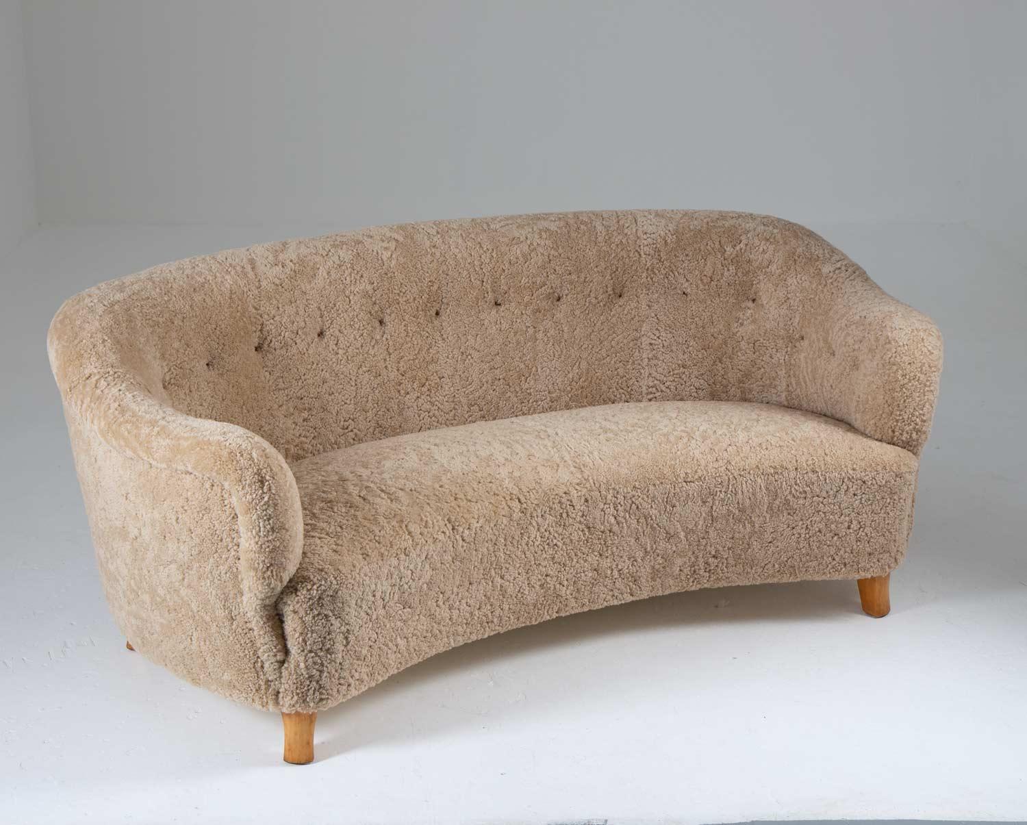 Curved 3-seater sofa attributed to Otto Schulz for Boet, Sweden.
High-quality sofa with organic lines, just as comfortable as it is beautiful. 
The sofa has been reupholstered in ivory-colored sheepskin and cognac leather buttons.

Condition: