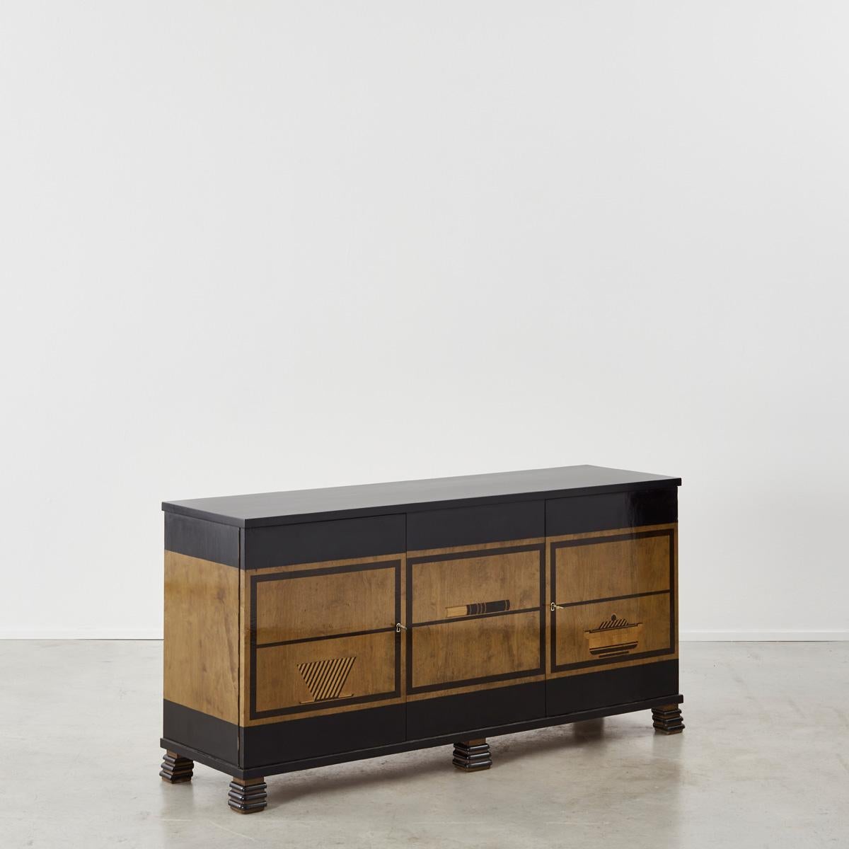 An extremely rare Boet sideboard featuring a trompe l’oeil decoration, blackened wood structure and walnut veneer. With cheeky, stacked feet and playful inlays that bring to mind an early take on pop art, this piece doesn’t take itself too
