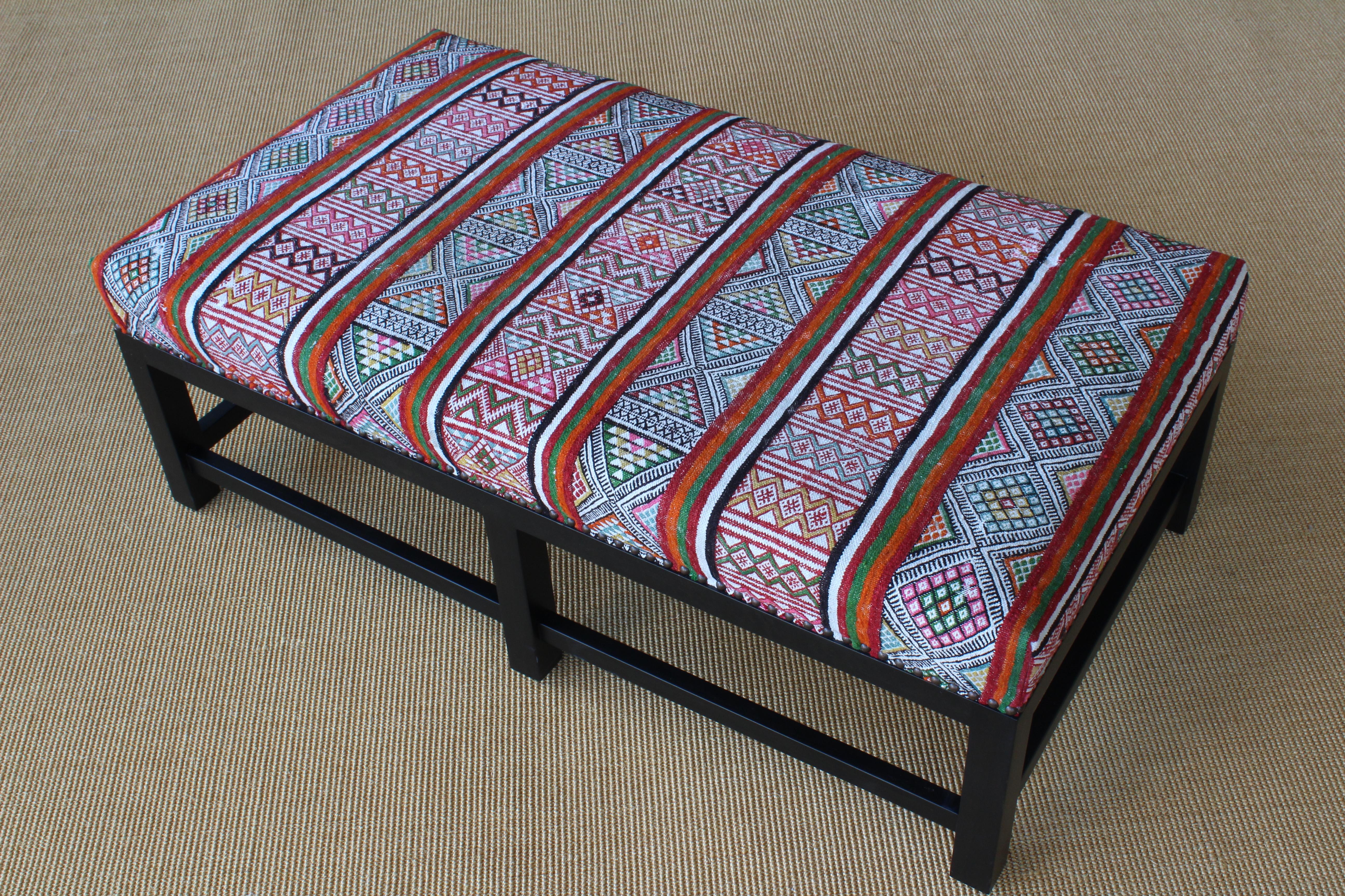 Custom ottoman with a solid wood base and upholstered in a vibrant vintage textile.
