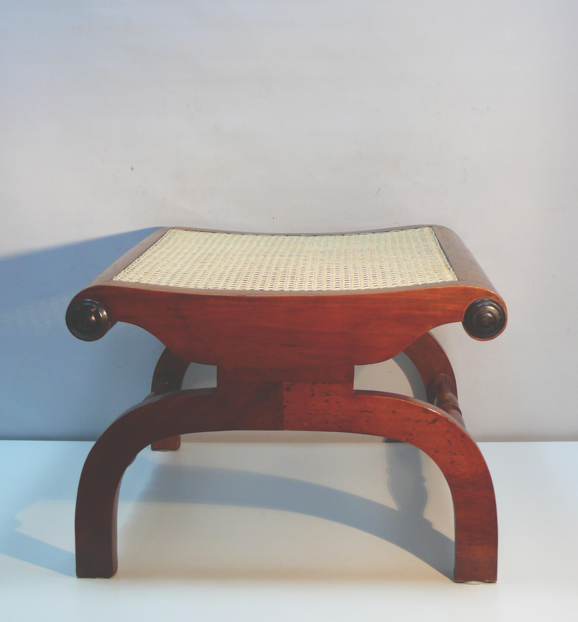 Rare seating option: Large ottoman made of solid teak with a cane-woven seat in the British colonial style. This generously sized stool was originally designed as a footstool for a comfortable armchair. The seat is gently curved, and the corners of