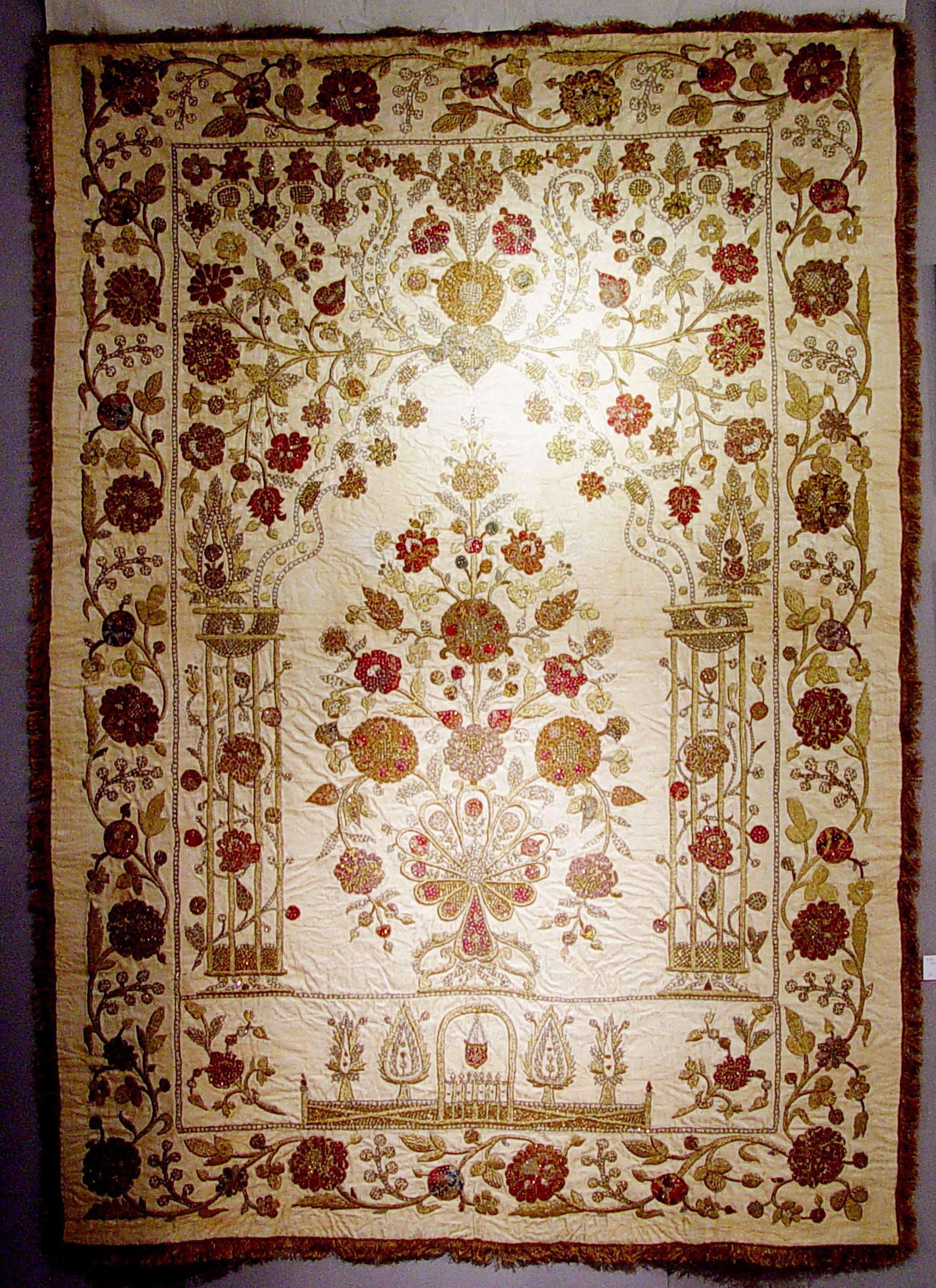 The Ottoman textile has gold embroidery on a beige satin silk background depicting flowers.

The massive silk work depicts the garden-like setting of heaven described in the Qur'an. It depicts an arched gateway, the gate to Paradise, in the center