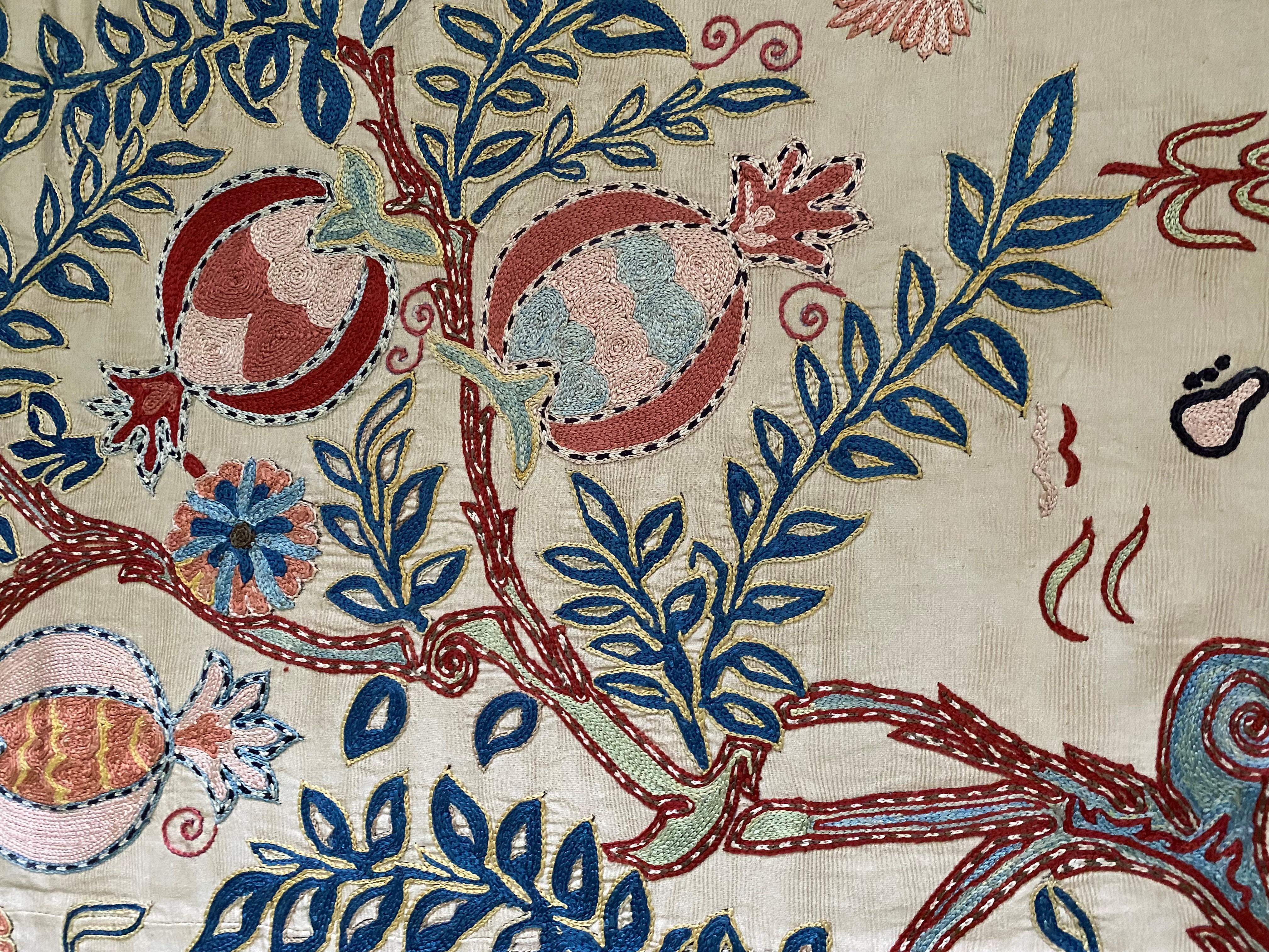 Unser osmanischer, handbestickter Suzani-Wandteppich mit Granatapfelmotiv aus Seide ist ein Meisterwerk traditioneller Handwerkskunst, reich an Geschichte und Kunstfertigkeit. Inspiriert von der Opulenz des Osmanischen Reiches, wird dieses exquisite