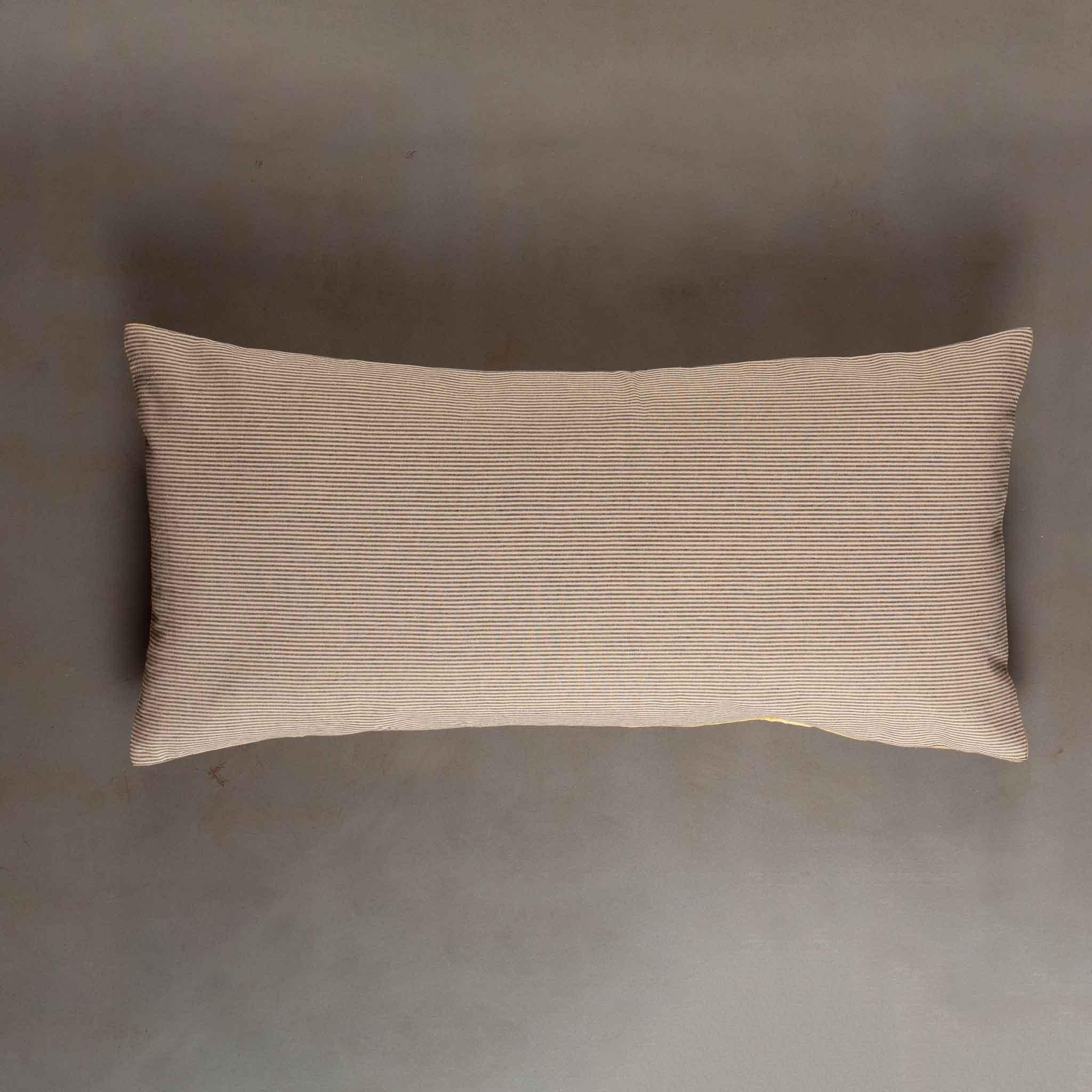 Ce coussin lombaire ancien présente un textile ottoman de la fin du XIXe siècle, richement brodé de soie et de laine. Au centre, un motif architectural en forme de dôme rayonne vers l'extérieur, encadré par des cachemires tourbillonnants et des
