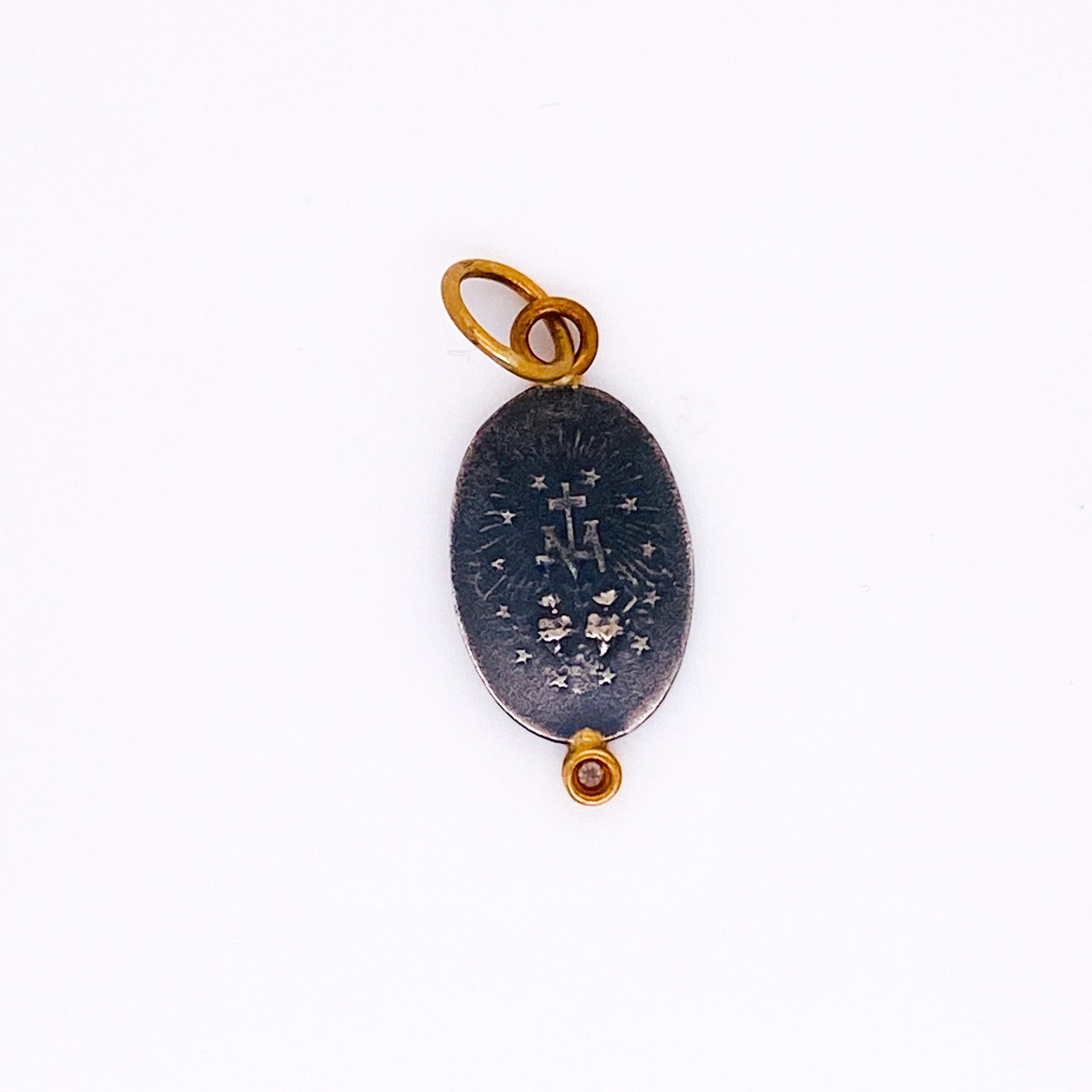 Ce pendentif est composé d'un charme en argent sterling inspiré d'une médaille miraculeuse des années 1850. La Mère Marie, ou Vierge Marie, est représentée avec des rayons de soleil encadrant sa figure, représentant la puissance de Dieu. Elle