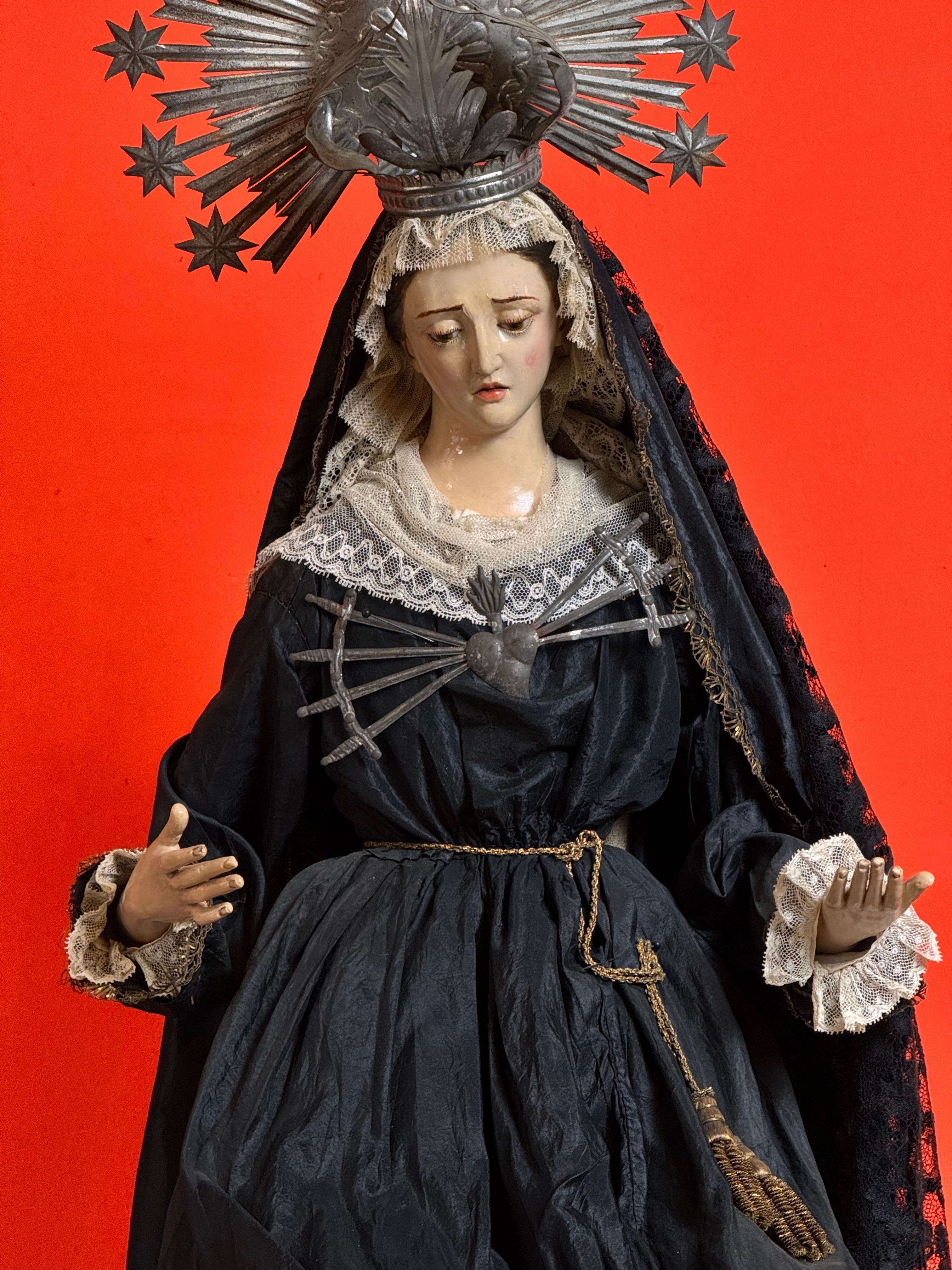Our Lady of Sorrows, dressed in robes, 19th century. 

This polychrome and gilded wooden sculpture features a delicately executed face, crystal tears, and glass eyes that accentuate the expression of sorrow. The Virgin is adorned with lace and a
