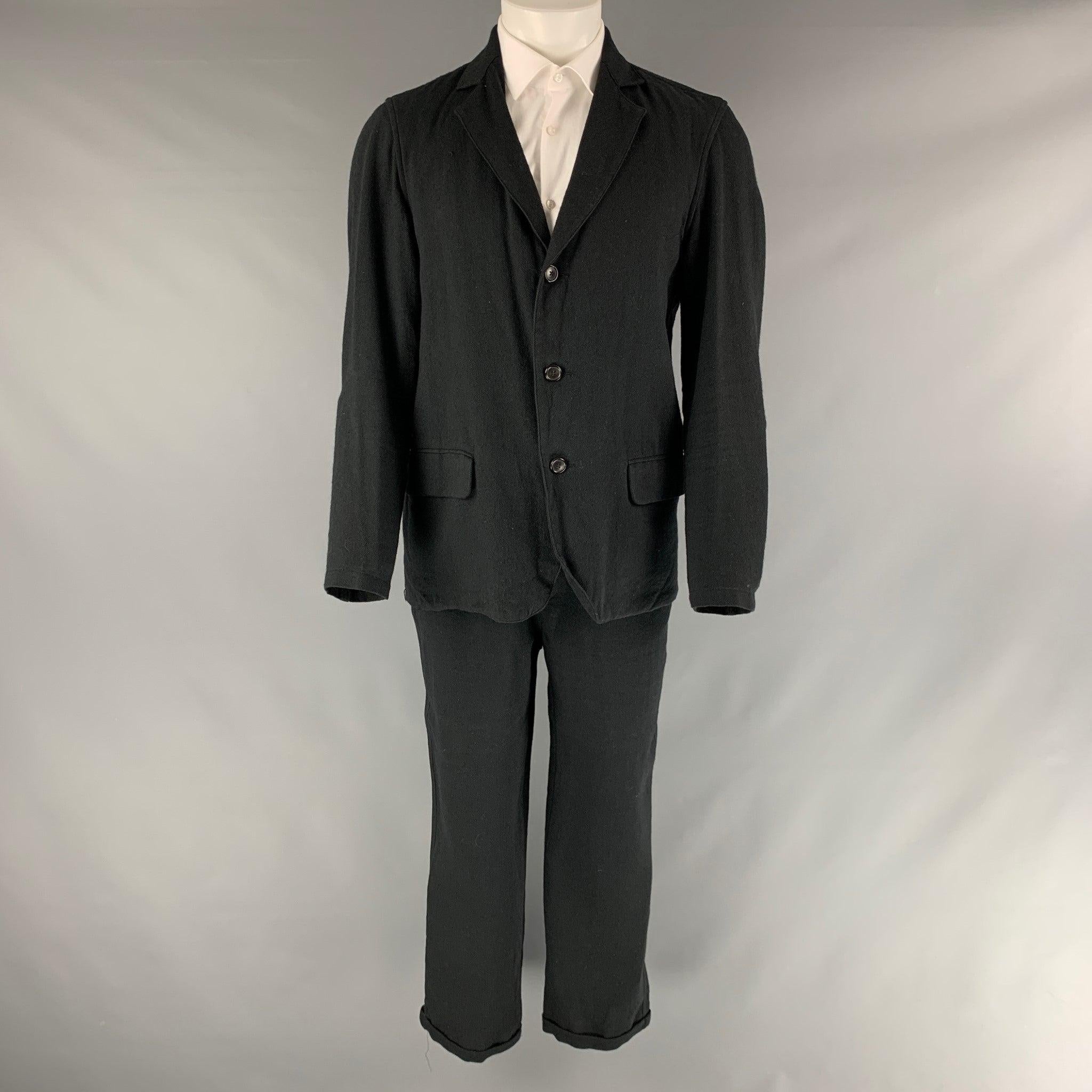 Notre costume surdimensionné LEGACY est réalisé dans un tissu noir en laine mélangée et comprend un manteau de sport à trois boutons, à revers échancré, et un pantalon assorti à taille élastique et cordon de serrage. Fabriqué au Japon. Excellent