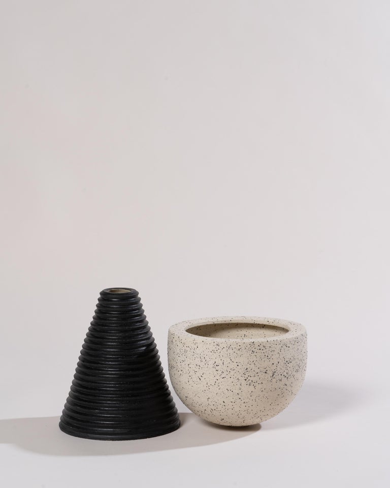 2-Part wheel-thrown planter in white stoneware with coarse black sand and black underglaze. The upper part features a drainage hole for optimal plant health, and the glaze-lined base collects excess water.