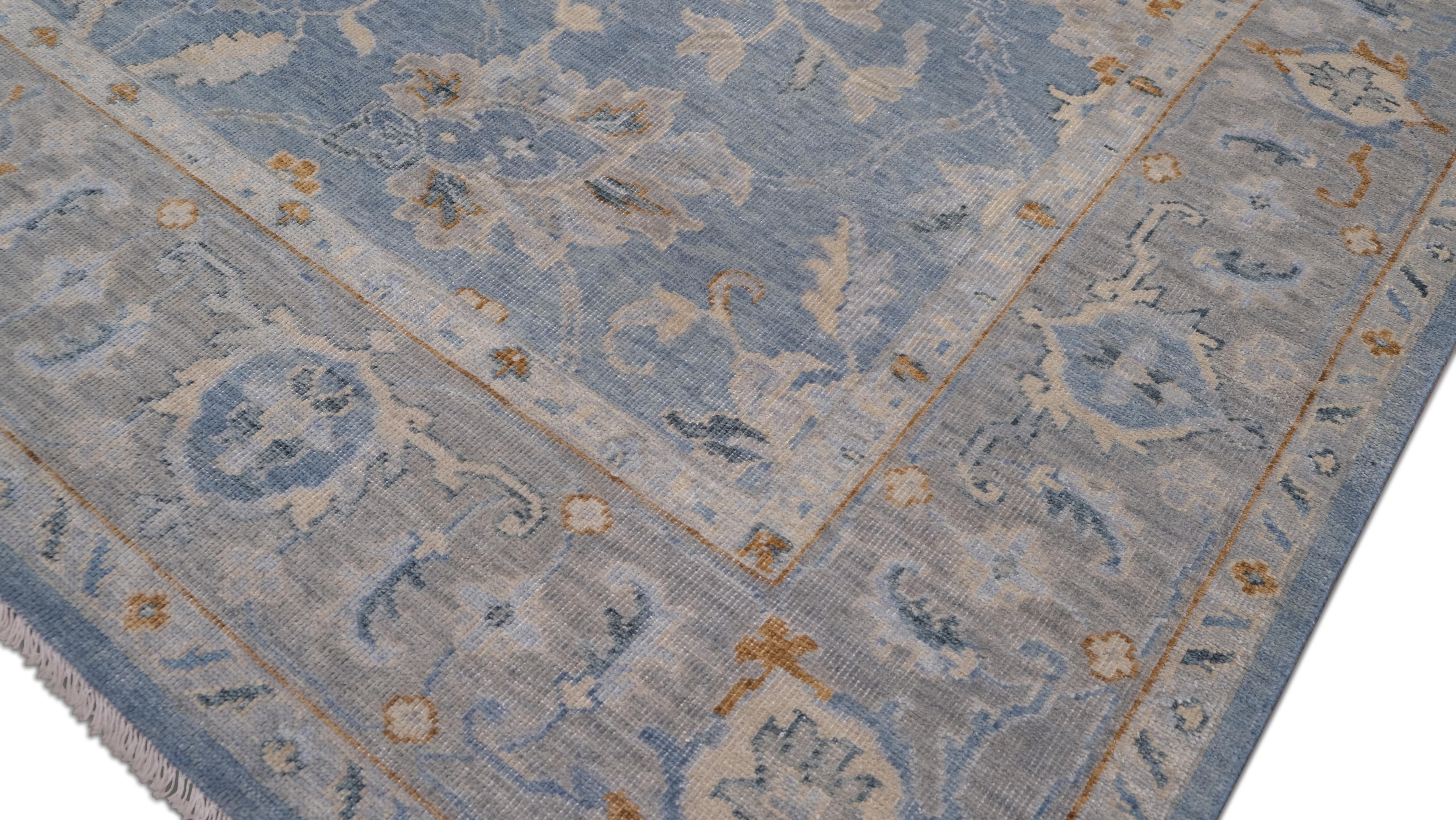 Questo tappeto in lana annodato a mano proveniente dall'India presenta un elegante disegno floreale tradizionale con intricati motivi a vite e un grande medaglione centrale. Il morbido sfondo blu del tappeto è splendidamente completato dal grigio,