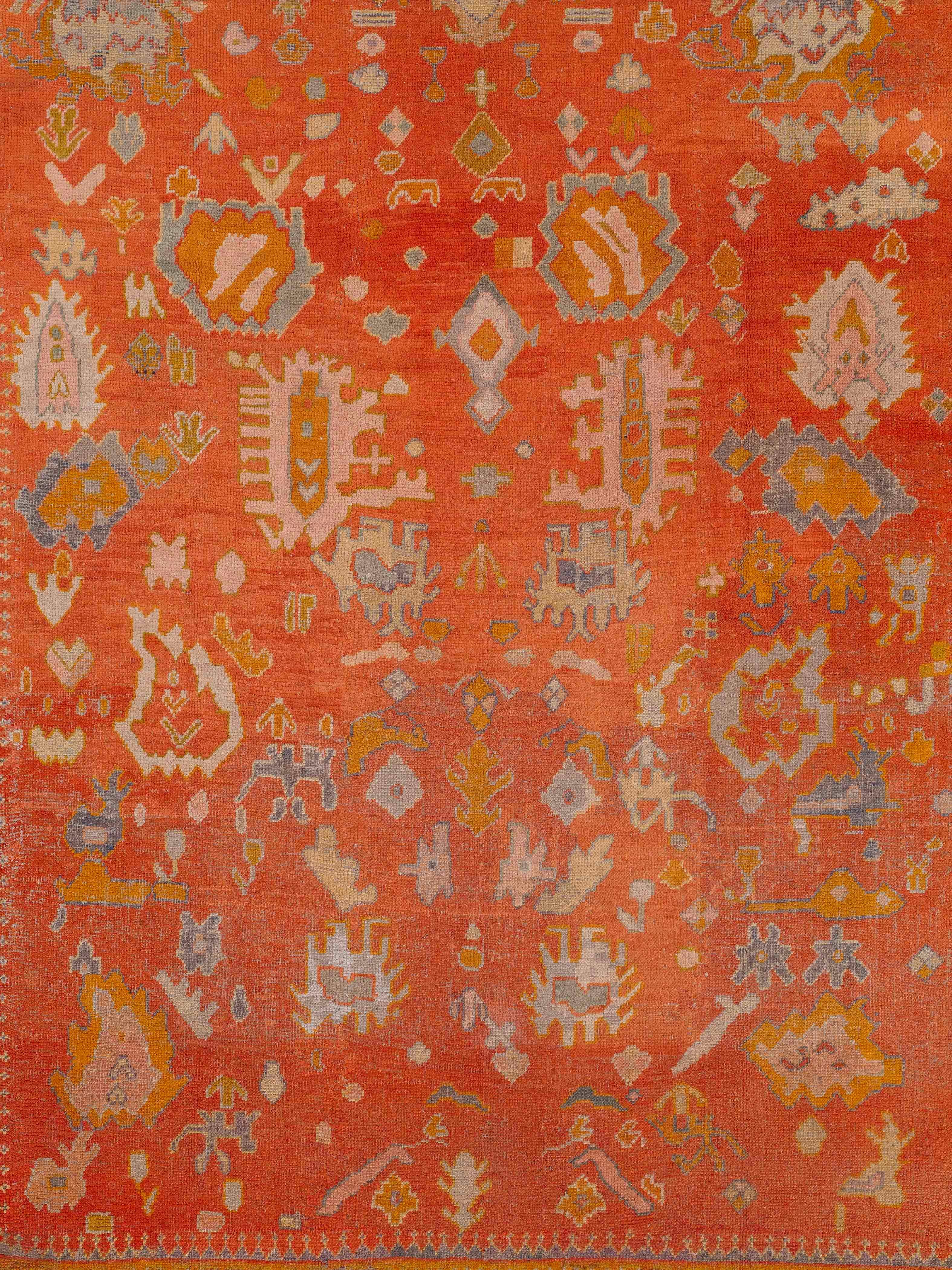 Le champ rouge gazpacho atténué est orné d'un médaillon graphique et d'un décor de têtes de fleurs, dans une bordure bleue et ocre doré. La qualité générale des poils et de la surface est peu usée et esthétiquement agréable, tout en conservant