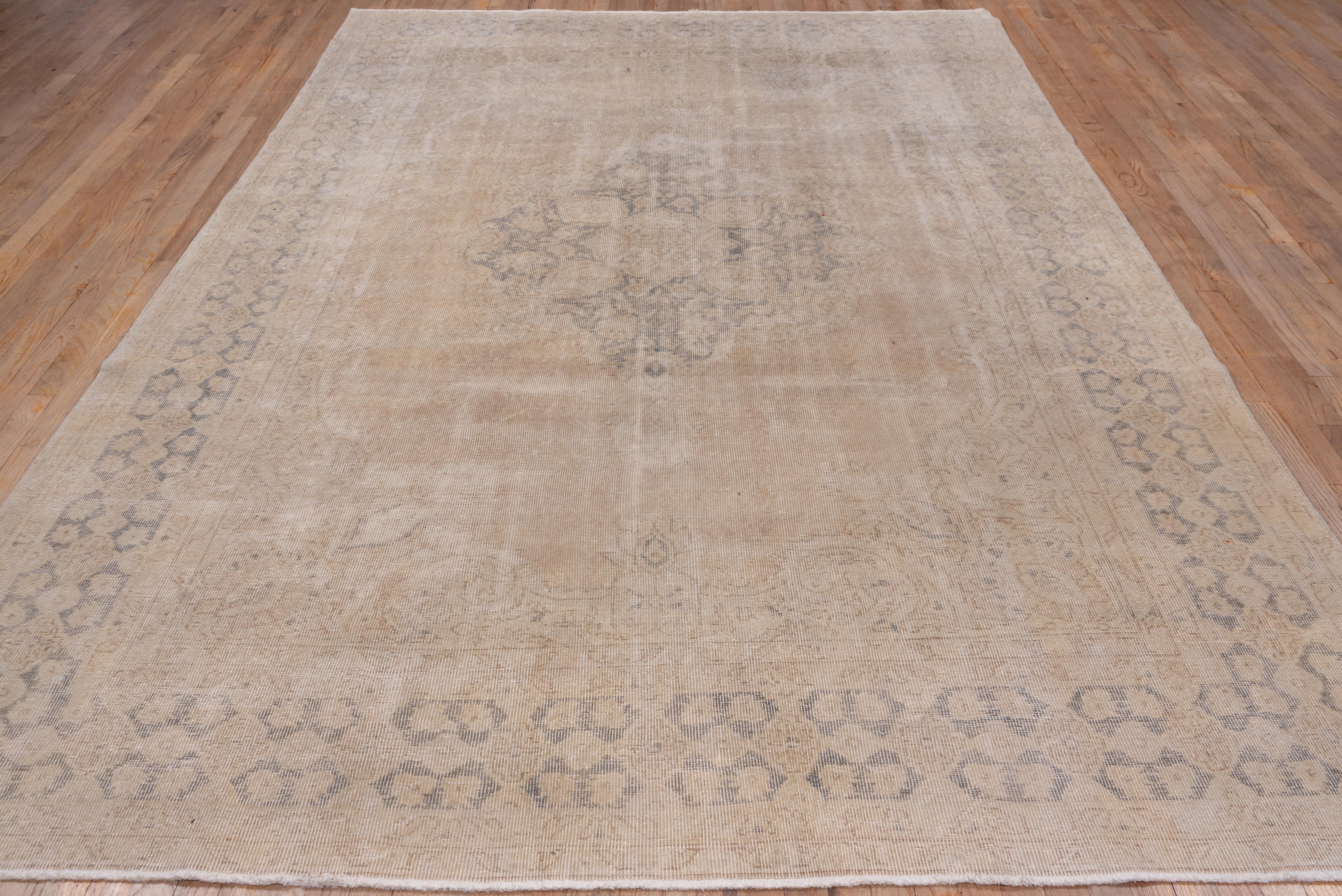 This western Turkish workshop carpet is in worn to distressed condition. The oval brown medallion centres the sandy beige field with acanthus arabesque corners. The brown main border shows a chain of rosettes-in-hexagons in a figure-ground color