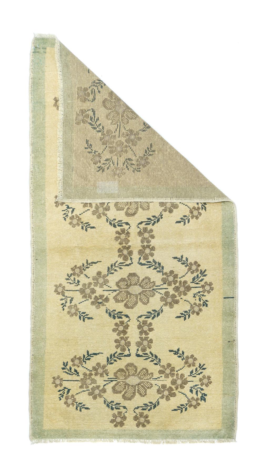 Alfombra Oushak 2'1'' x 6'2''. Una cadena floral hace zigzag, zag y corre recta para encerrar cuatro palmetas de pétalos moteados en rosa-coral y marrón oscuro sobre el fondo de paja arenosa. Otras ramitas de flores contornean las curvas de las