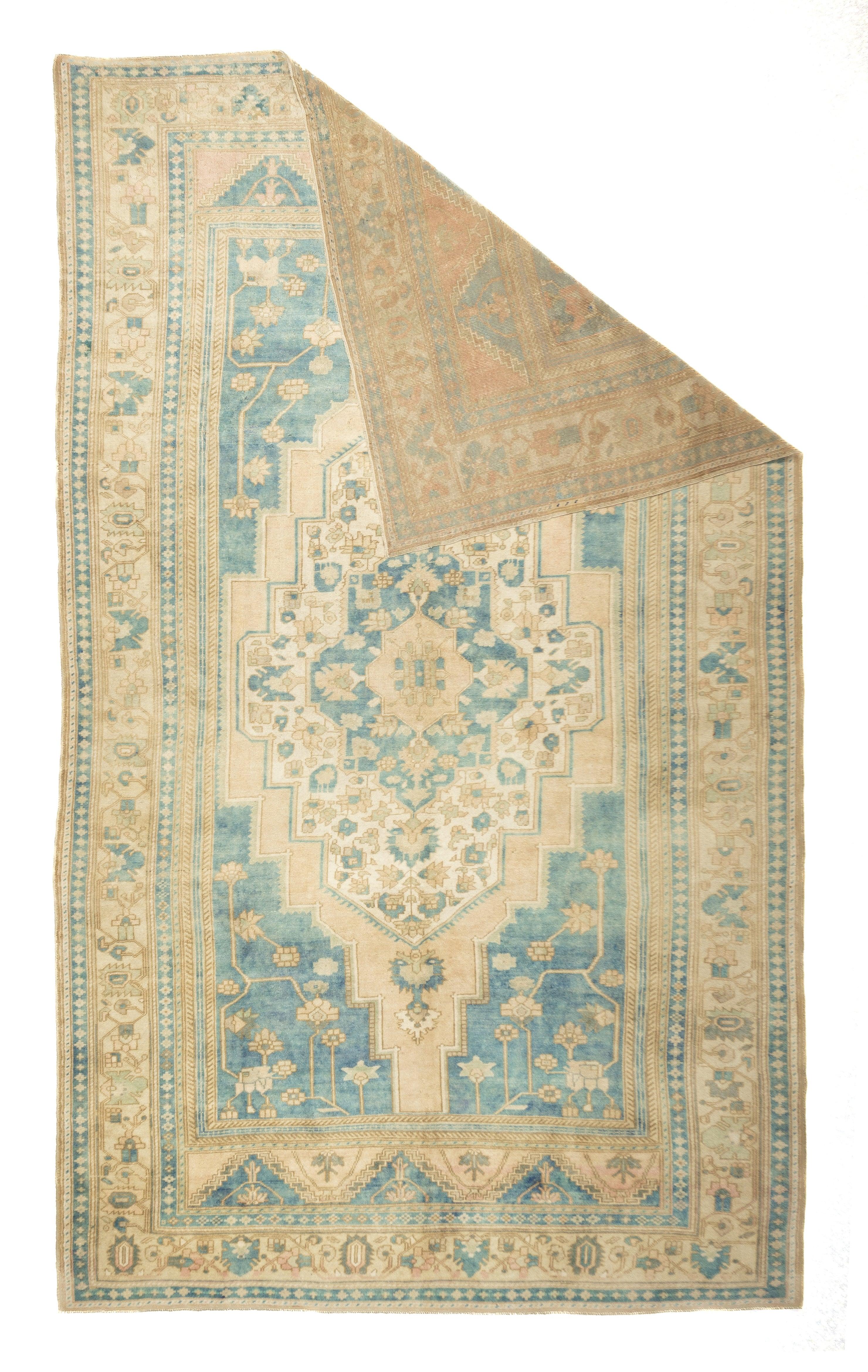 Oushak Rug 7'7'' x 11'7''. The and hosts a tall stepped, and pointed ecru medallion accented with small palmettes. Blue and cream triangle and rhomboid end panels. narrow buff open field is positioned by light blue irregularly stepped corners. Straw
