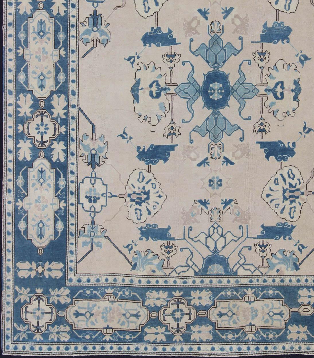 Vintage Turkish Oushak in cream and blue, rug en-165875, country of origin / type: Turkey / Oushak, circa 1940

This tribal design Oushak carpet features an array of motifs expanding across the central field. The thick border features a large