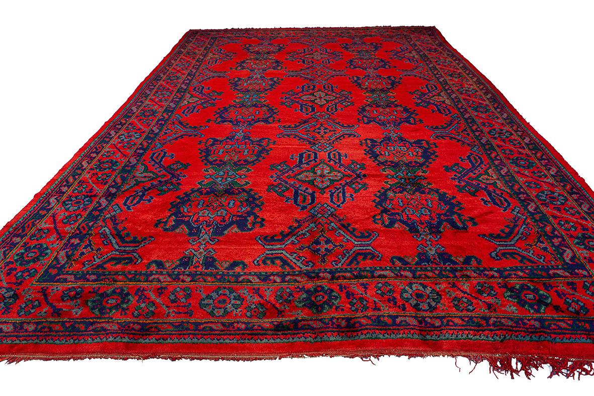 Dieser prächtige Oushak-Teppich in roter Farbe mit den beeindruckenden Maßen 455 × 309 cm ist ein großartiges Beispiel osmanischer Kunstfertigkeit und Handwerkskunst. Die satten, satten Farben und komplizierten Muster des Teppichs sind ein visuelles