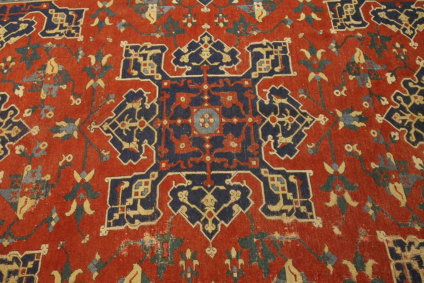 Dieser Oushak-Teppich mit den Maßen  185 x 340 cm, zeigt die charakteristischen Merkmale der türkischen Webtradition. Das tiefrote Feld ist mit großen, geometrischen Medaillons und floralen Motiven verziert, die durch marine- und elfenbeinfarbene