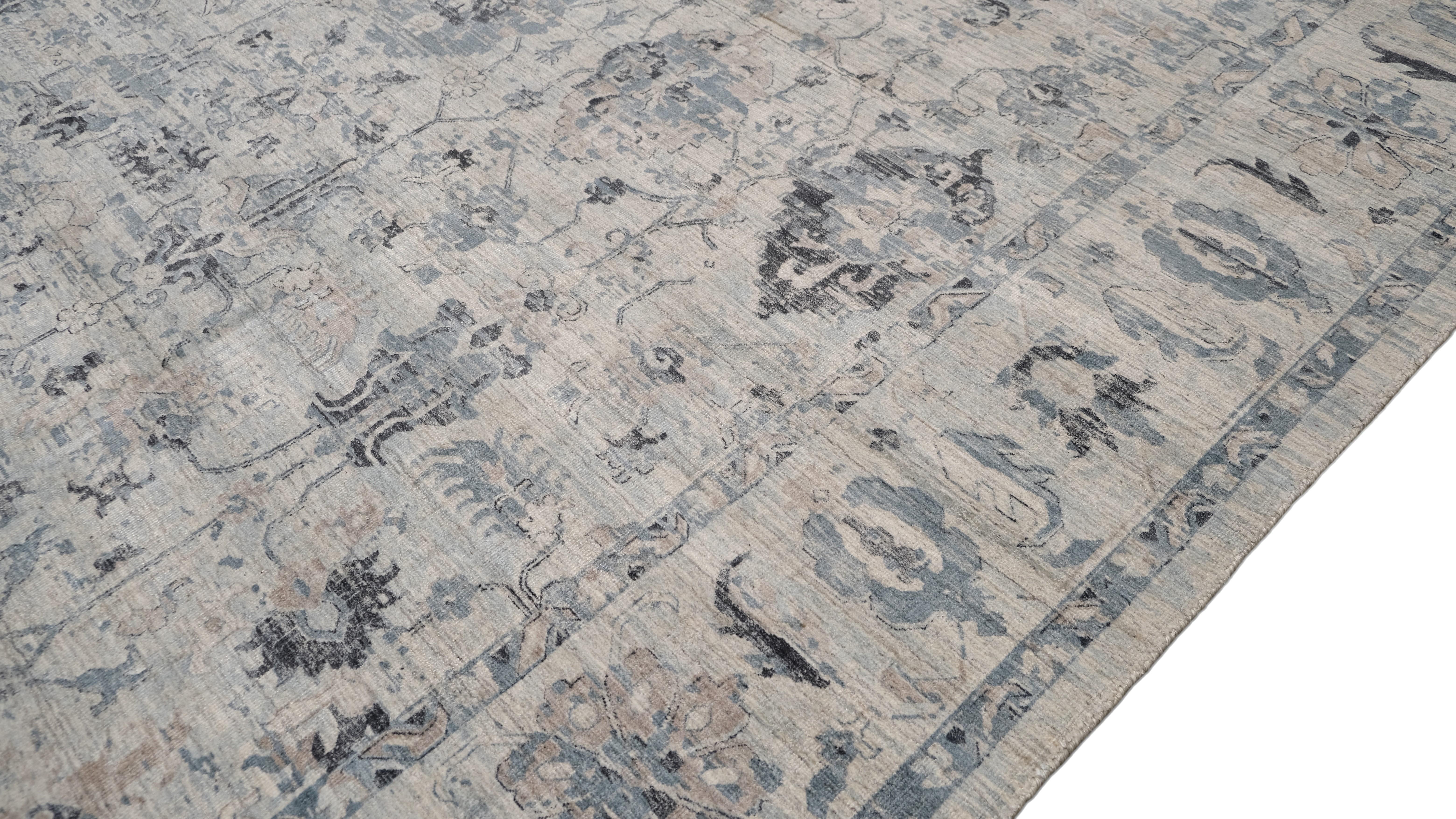 Dieser handgefertigte Teppich aus Wolle und Viskose zeigt eine zarte, sanfte Farbpalette in Blau und Elfenbein, die seine eleganten Blumen- und Rankenmotive hervorhebt. Das Design ist von klassischen und traditionellen indischen Mustern inspiriert