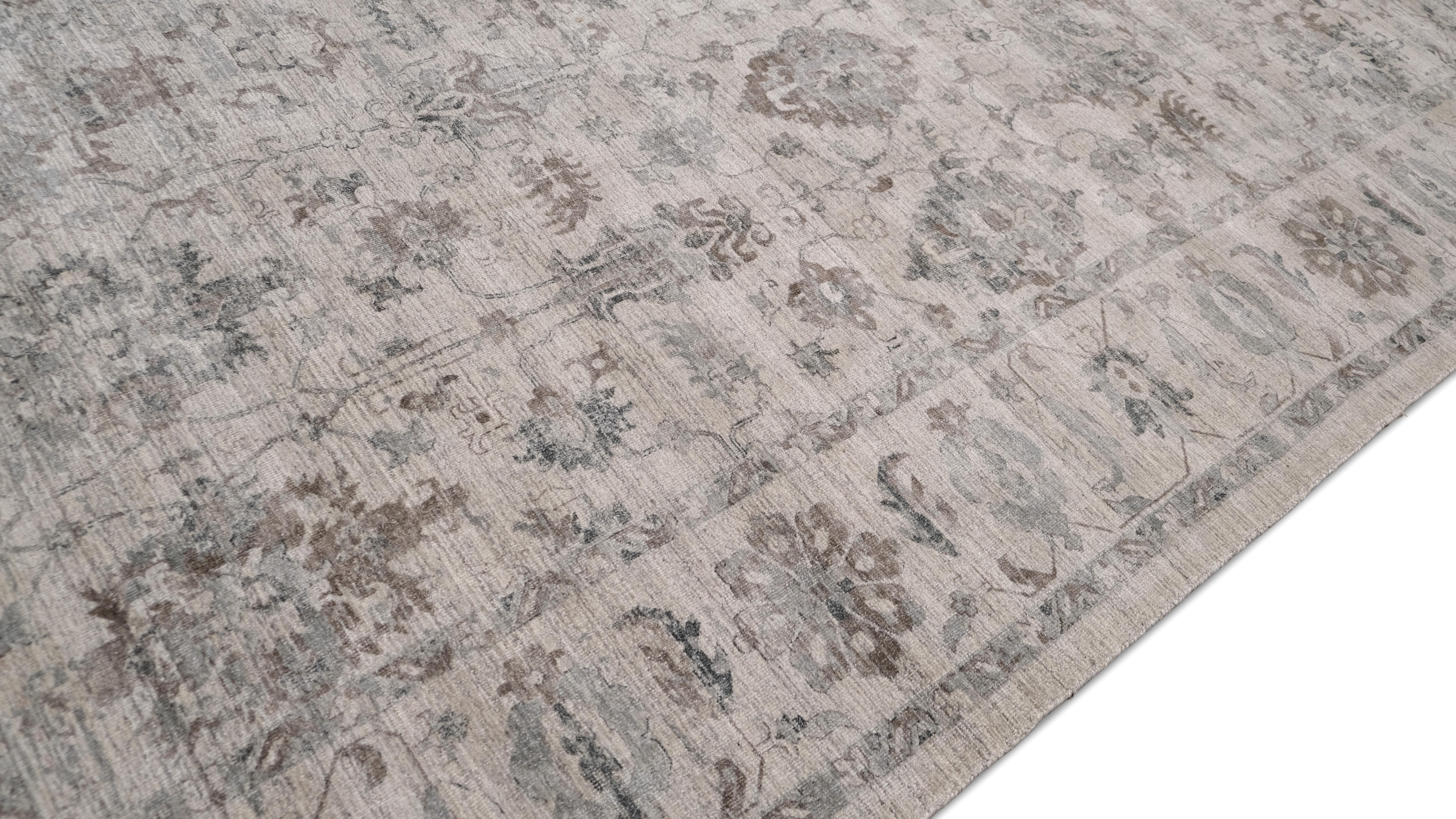 Dieser handgefertigte Teppich aus Wolle und Viskose zeichnet sich durch eine raffinierte Mischung aus weichen Grau- und Elfenbeintönen aus, die ein zeitloses und vielseitiges Design schaffen. Die zarten floralen Motive und das filigrane