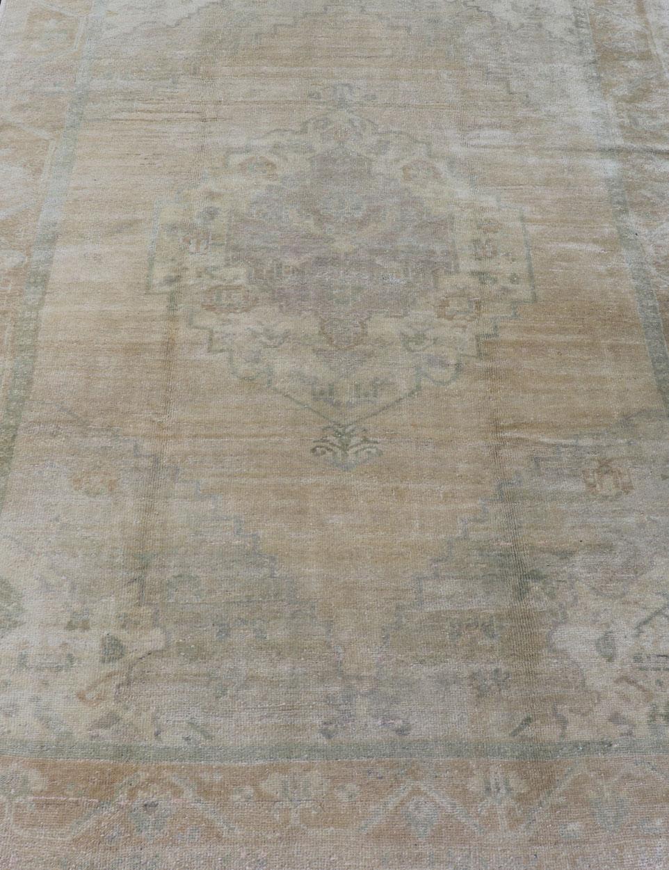 Alfombra Vintage Oushak de color claro con medallón central de diseño desteñido. Alfombra EN-112333, país de origen / tipo: Turquía / Oushak, hacia mediados del siglo XX.

Esta alfombra turca Oushak vintage (de mediados del siglo XX) presenta una