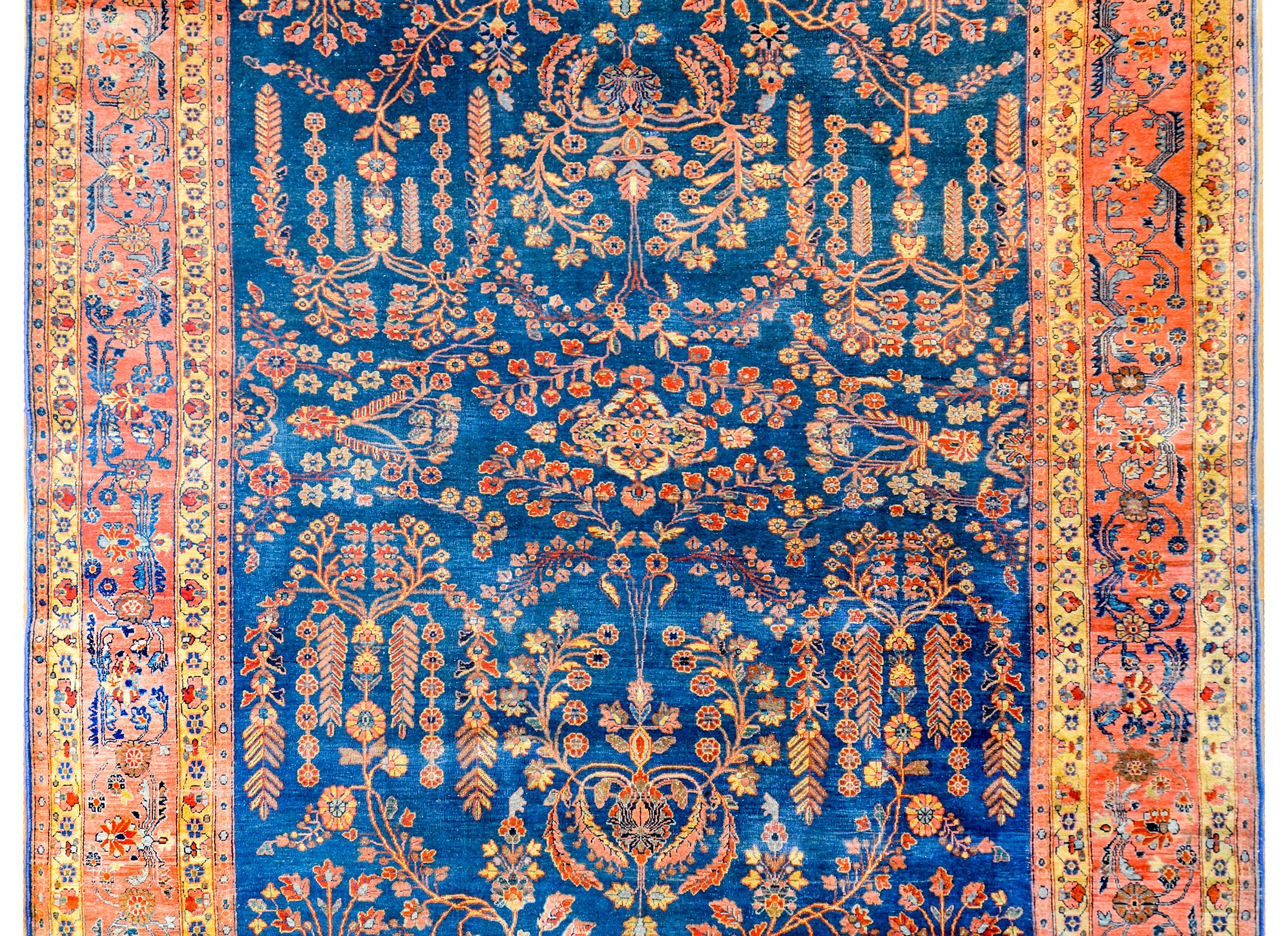 An outstanding early 20th century Persian Sarouk rug with a beautiful mirrored tree-of-life pattern woven in crimson, gold, and pink, in a rich indigo background. The border is gorgeous, with a wonderful scrolling leaf, vine, and floral pattern on a