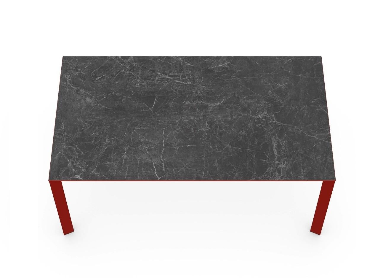 Table de salle à manger fixe avec base à quatre pieds. Pieds et structure laqués de couleur rouge. Plateau de table en céramique, finition marbre grec noir.
Autre version disponible avec un cadre en métal et un plateau en verre peint. 
Dimensions