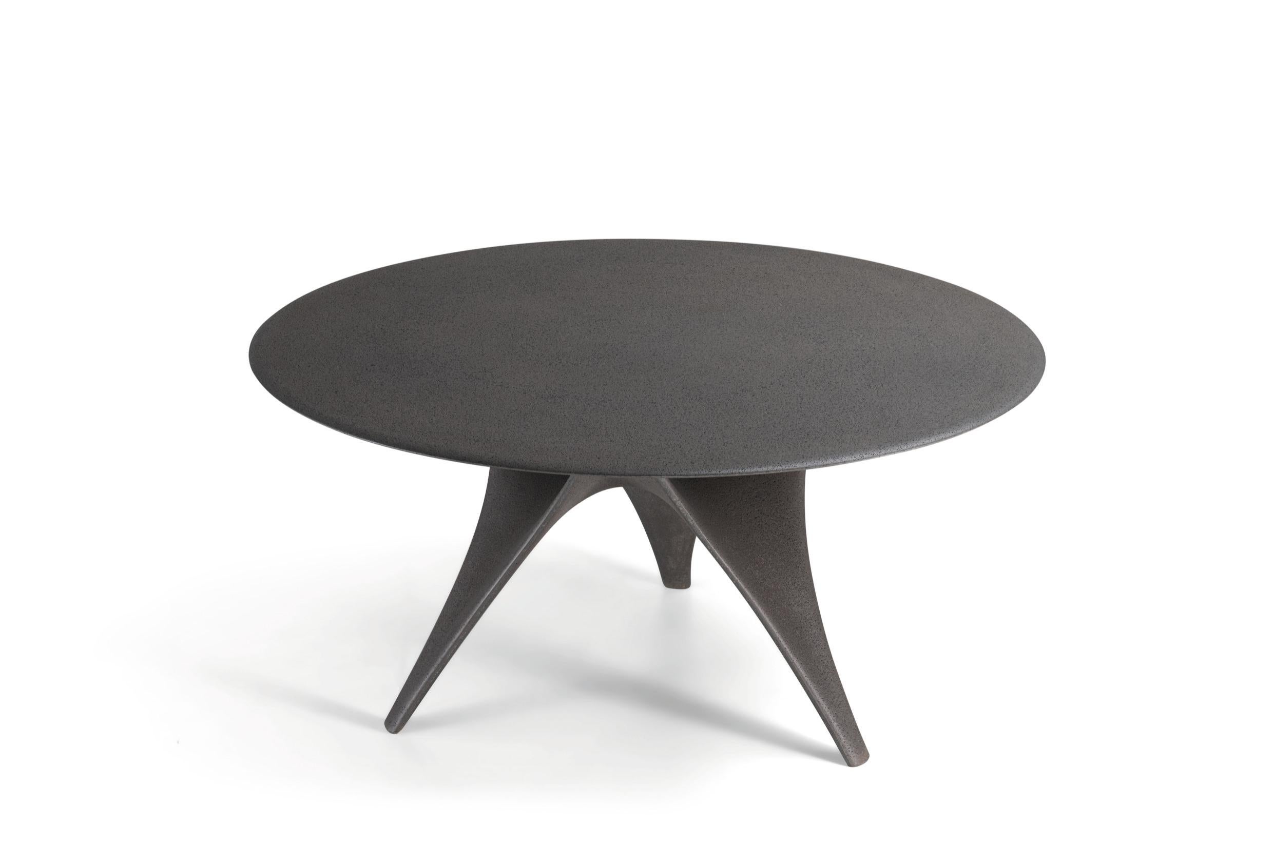 La table Arc de Foster + Partners a été réimaginée pour la vie en plein air, avec une finition tout en ciment. En gris Dolomite, mono-matériau et finition monochrome, cette version résistante aux intempéries incarne les mêmes formes fluides que