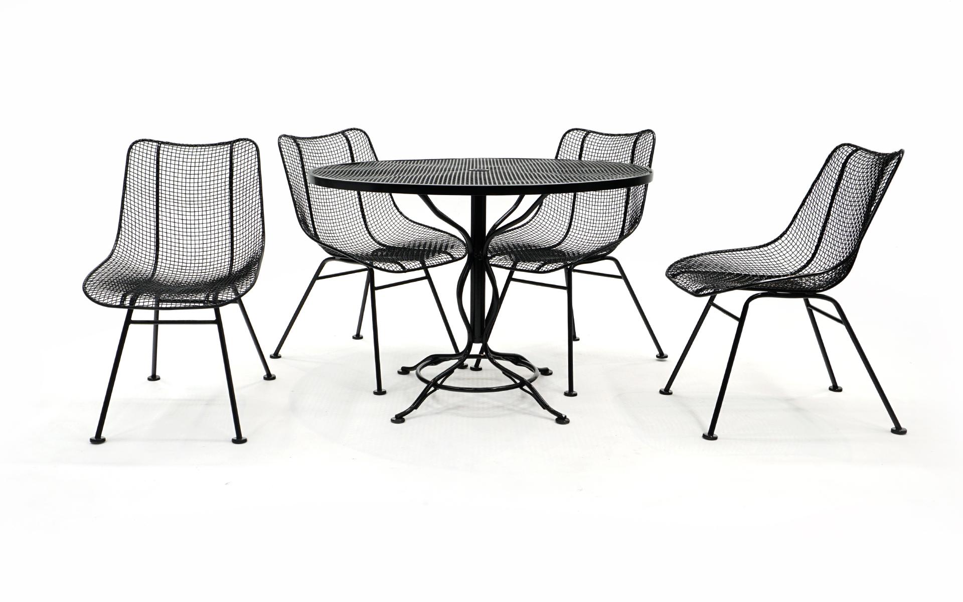 John Woodard outdoor dining set consisting of a round table and four woven wire Sculptura chairs (often misattributed to Russel Woodard). Professionally sand blasted and painted in a black gloss automotive finish. More durable and long lasting than