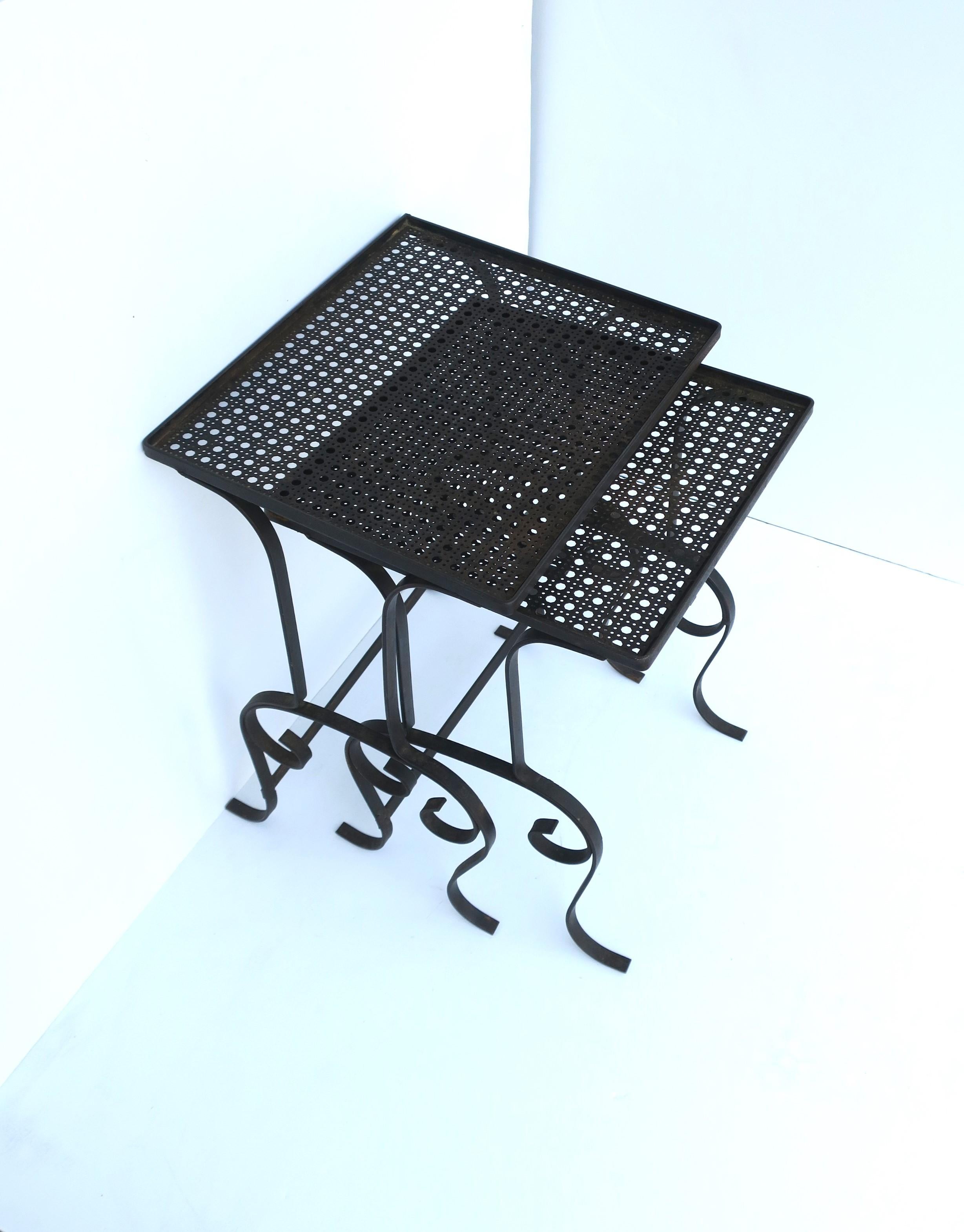 A pair/set of outdoor side drinks nesting tables with metal cane tops, circa early to mid-20th century. This set/pair of iron metal tables have a dark brown patina, 'cane' perforated tops, and scrolled legs. A great set for drinks and a small bite.