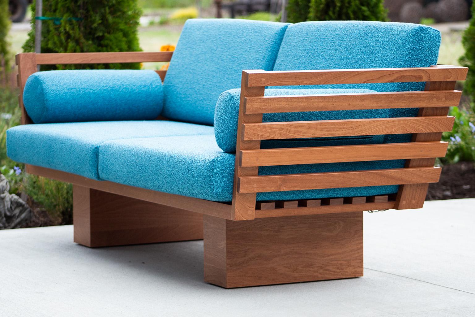 Dieses moderne Terrassenmöbel - Suelo Slatted Loveseat ist wunderschön in Ohio, USA, gefertigt. Diese Silhouette ist einfach, modern und schlank mit bequemen Rücken- und Sitzkissen. Der Holzrahmen ist für den Einsatz im Freien geeignet und mit einer