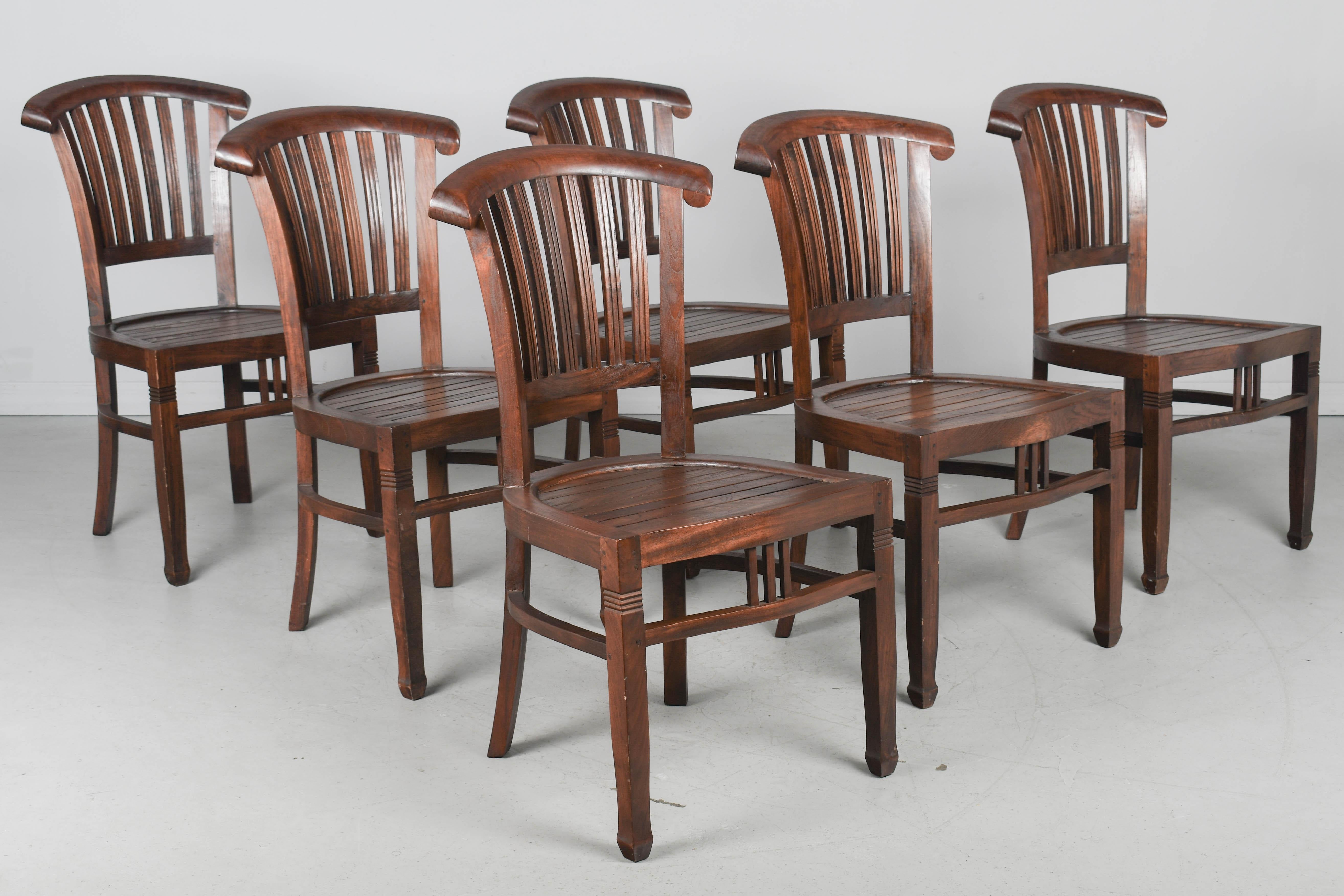 Un set di sei sedie da pranzo per esterni in legno duro di teak. Sedie robuste e ben costruite, con schienale a doghe e sponda superiore curva.  
Dimensioni: 36,25 