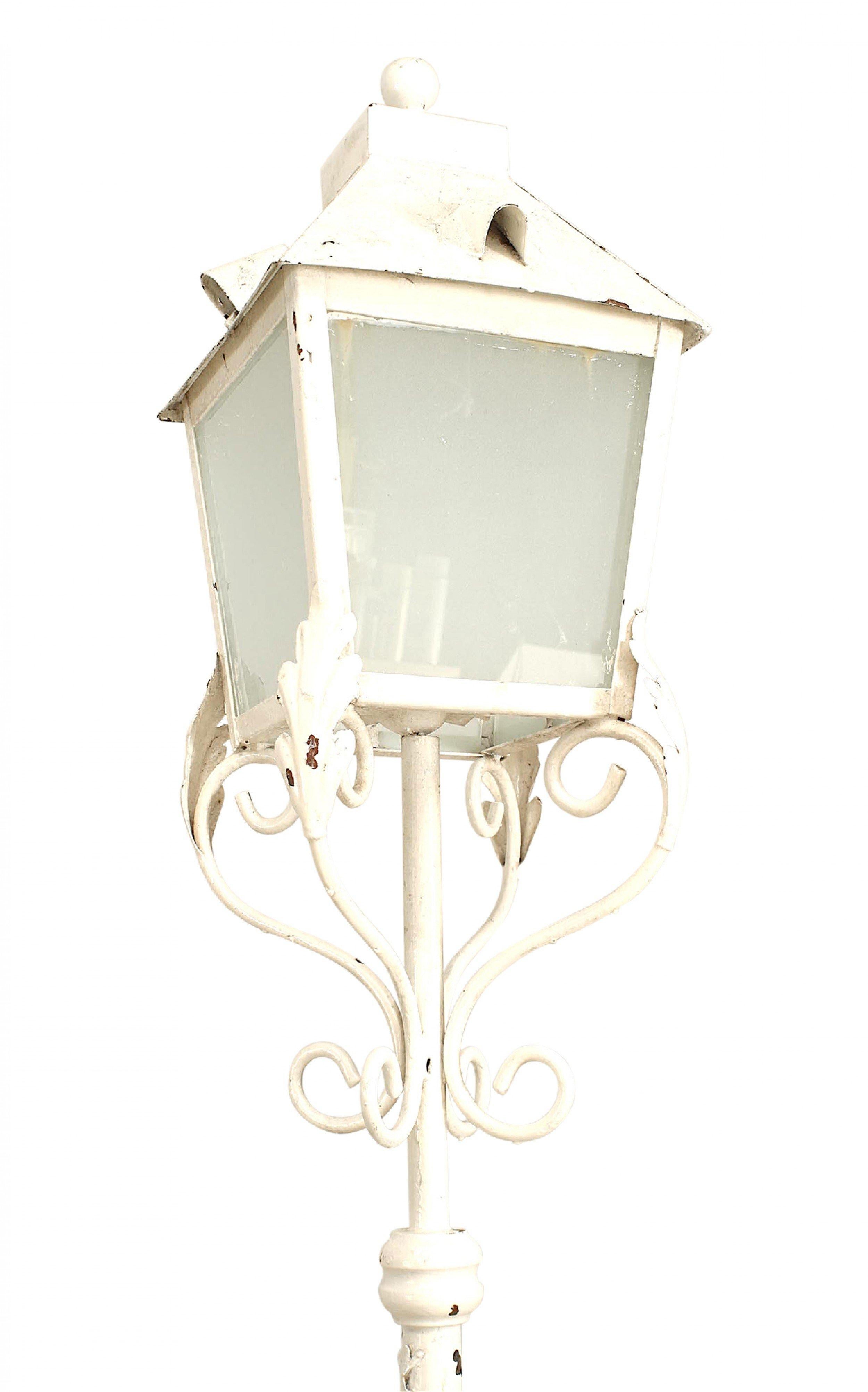 2 outdoor white painted iron floor lamps standing on 4 scroll legs with a 4 glass panel lantern top (priced each).
  
